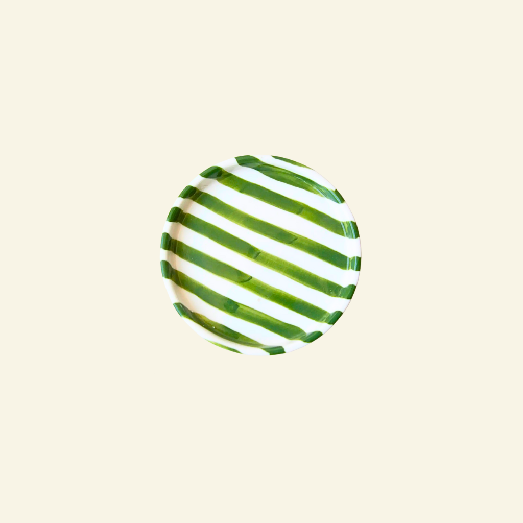 Green and white striped ceramic plate on a beige background