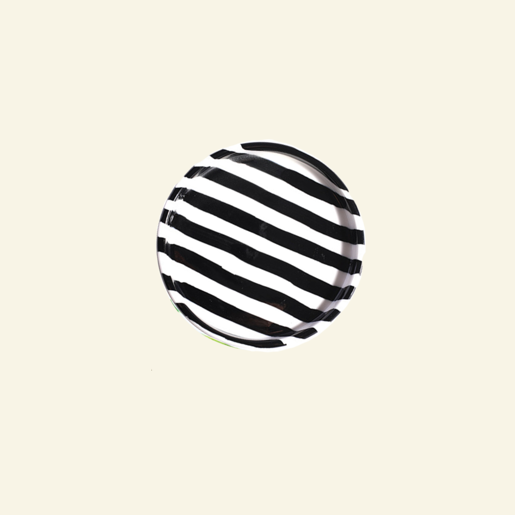 Black and white striped artisan handmade ceramic plate on a beige background