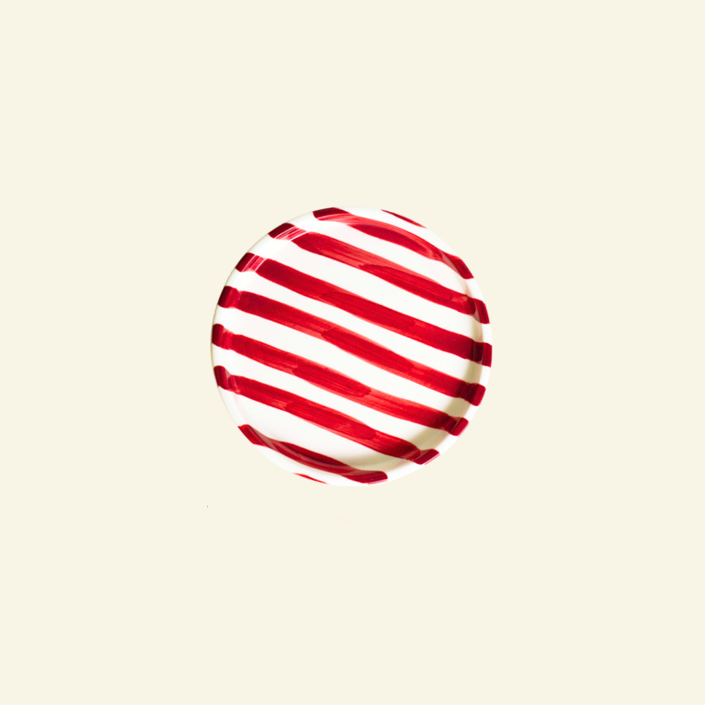 Red and white striped artisan handmade ceramic plate on a beige background