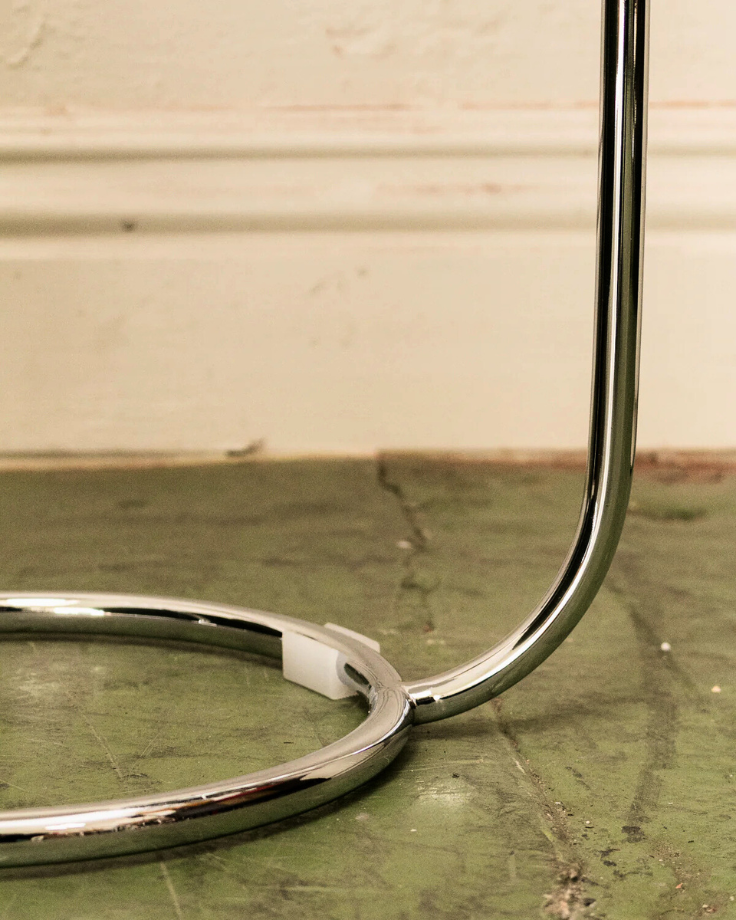 Close-up of a chrome metal ring on a green surface with a beige wall background