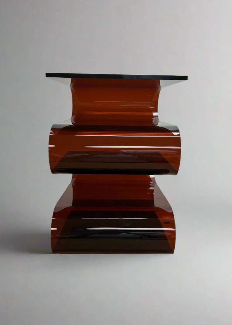 Modern acrylic s-shaped side table with a glossy brown base and clear glass top on a gray background