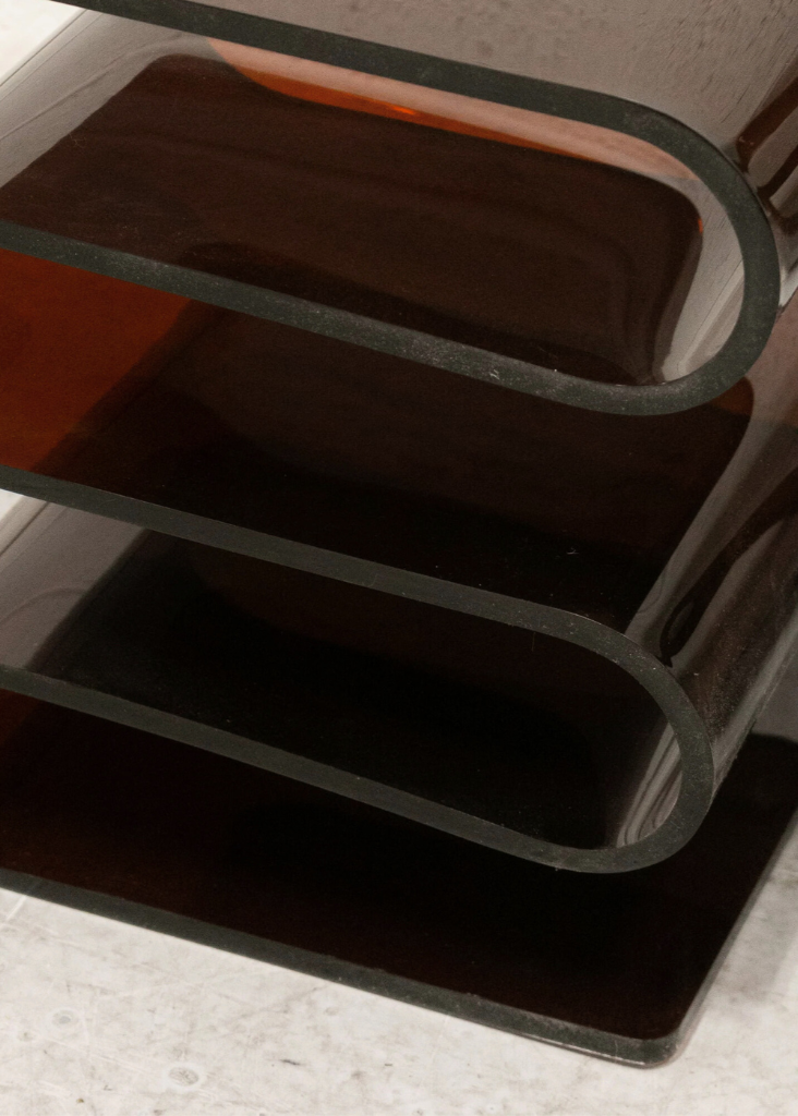 Acrylic S-Shaped Side Table in amber brown on a light gray floor.