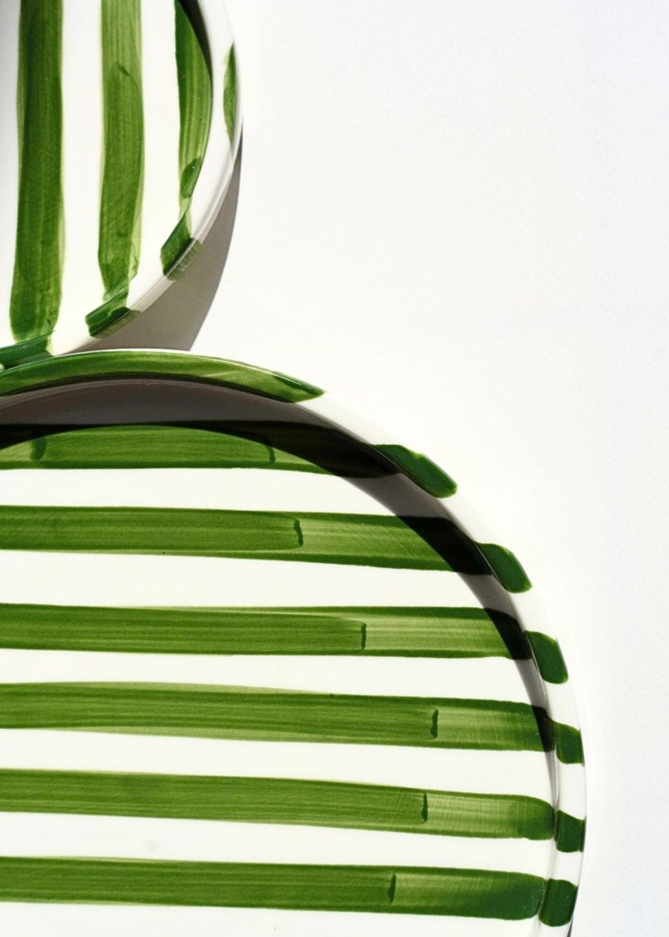 Round Artisan Ceramic Plate (Small) and (Large) with green and white striped pattern on a beige background