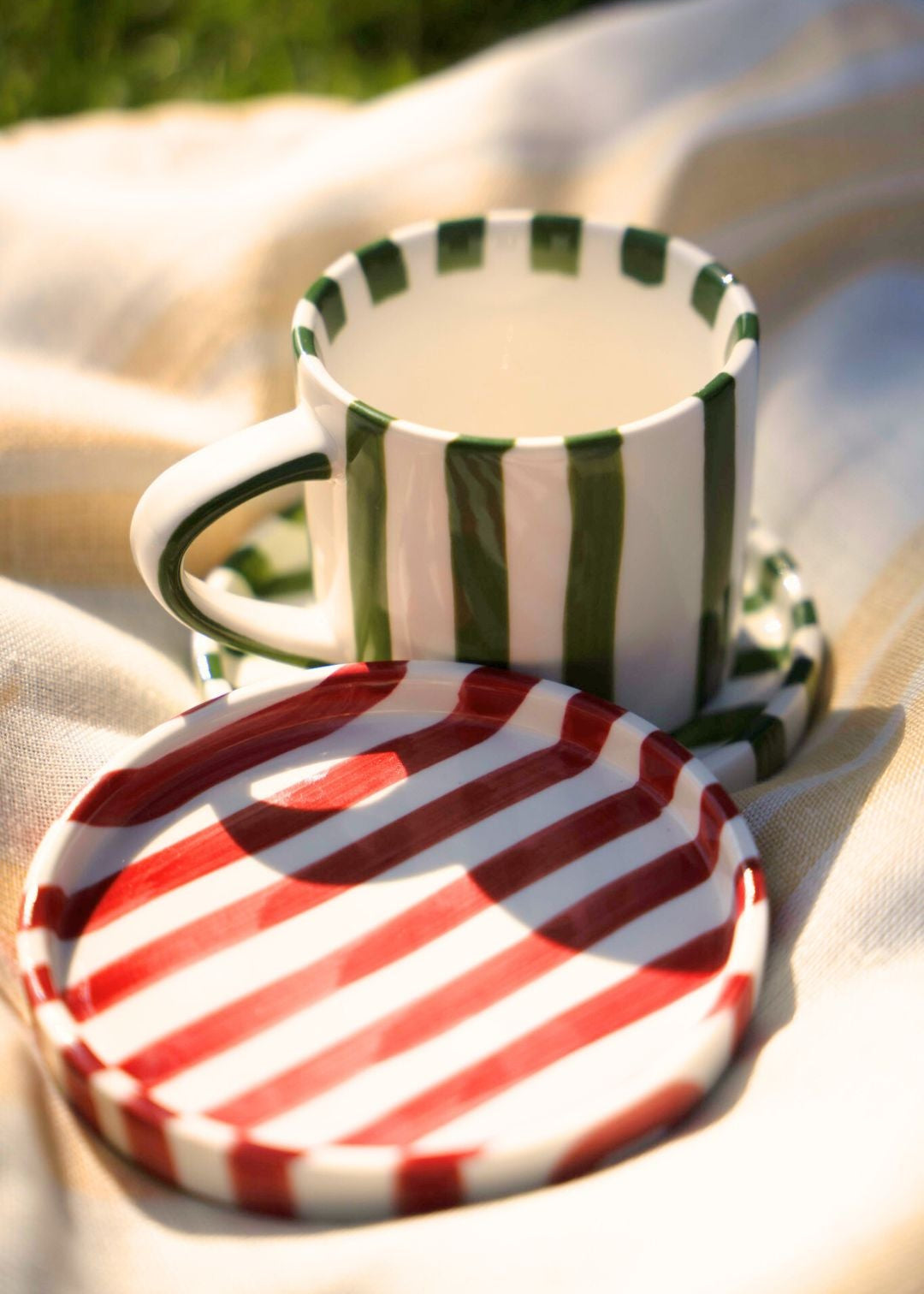 Round Artisan Ceramic Plate (Small) with green and white striped pattern and red and white striped pattern on a beige background