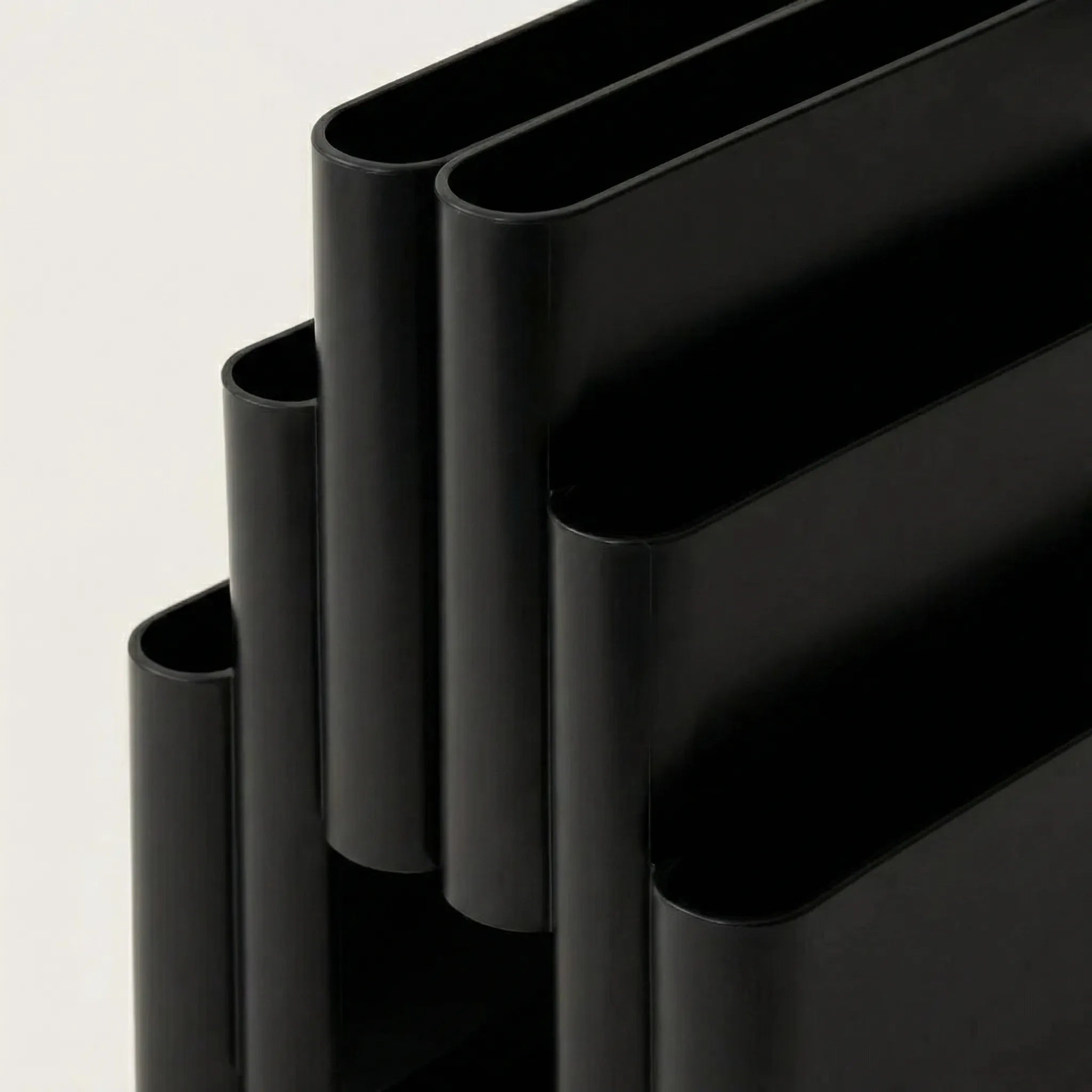 Close-up of Black kartell magazine rack replica on a white surface