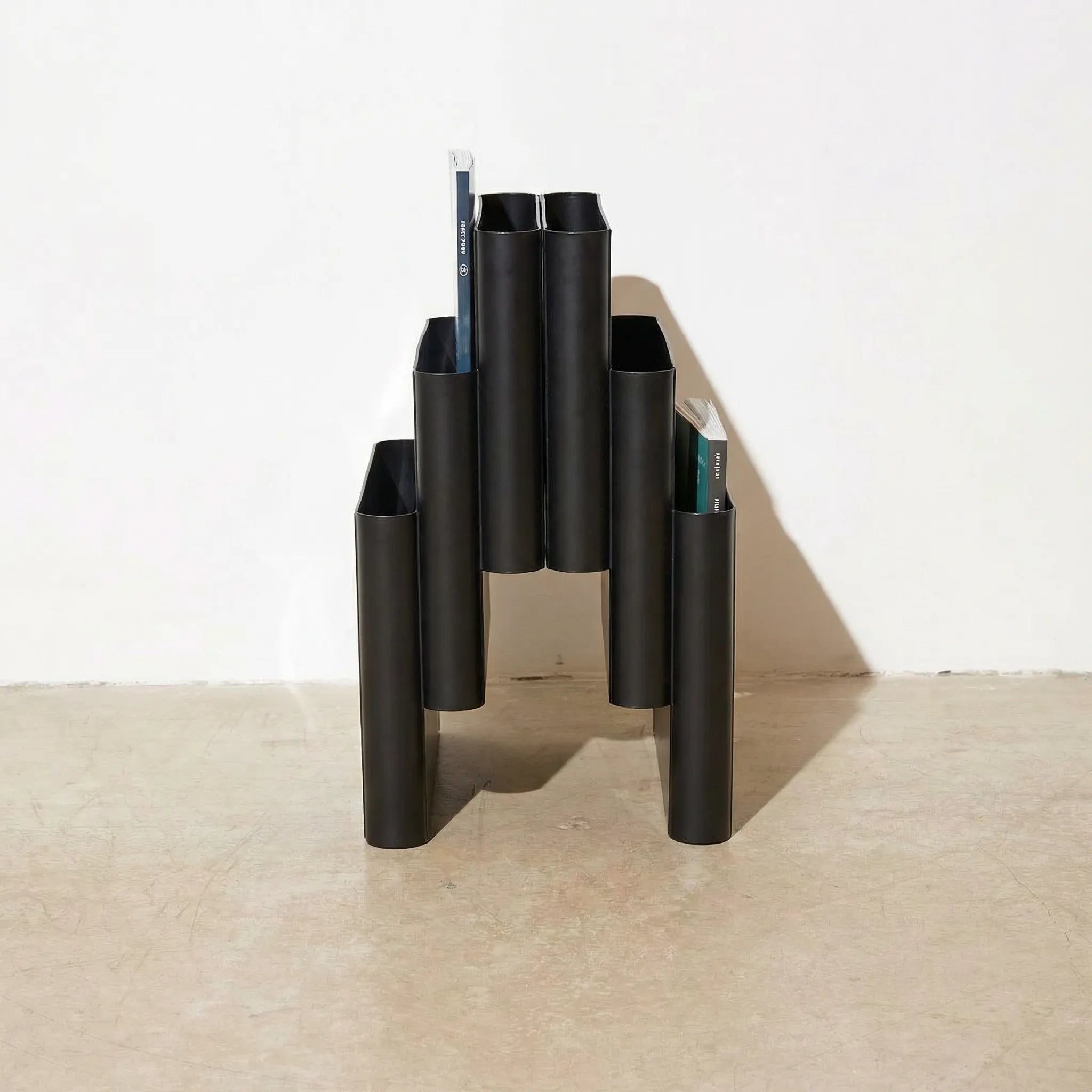 Black Kartell magazine rack replica on a white surface