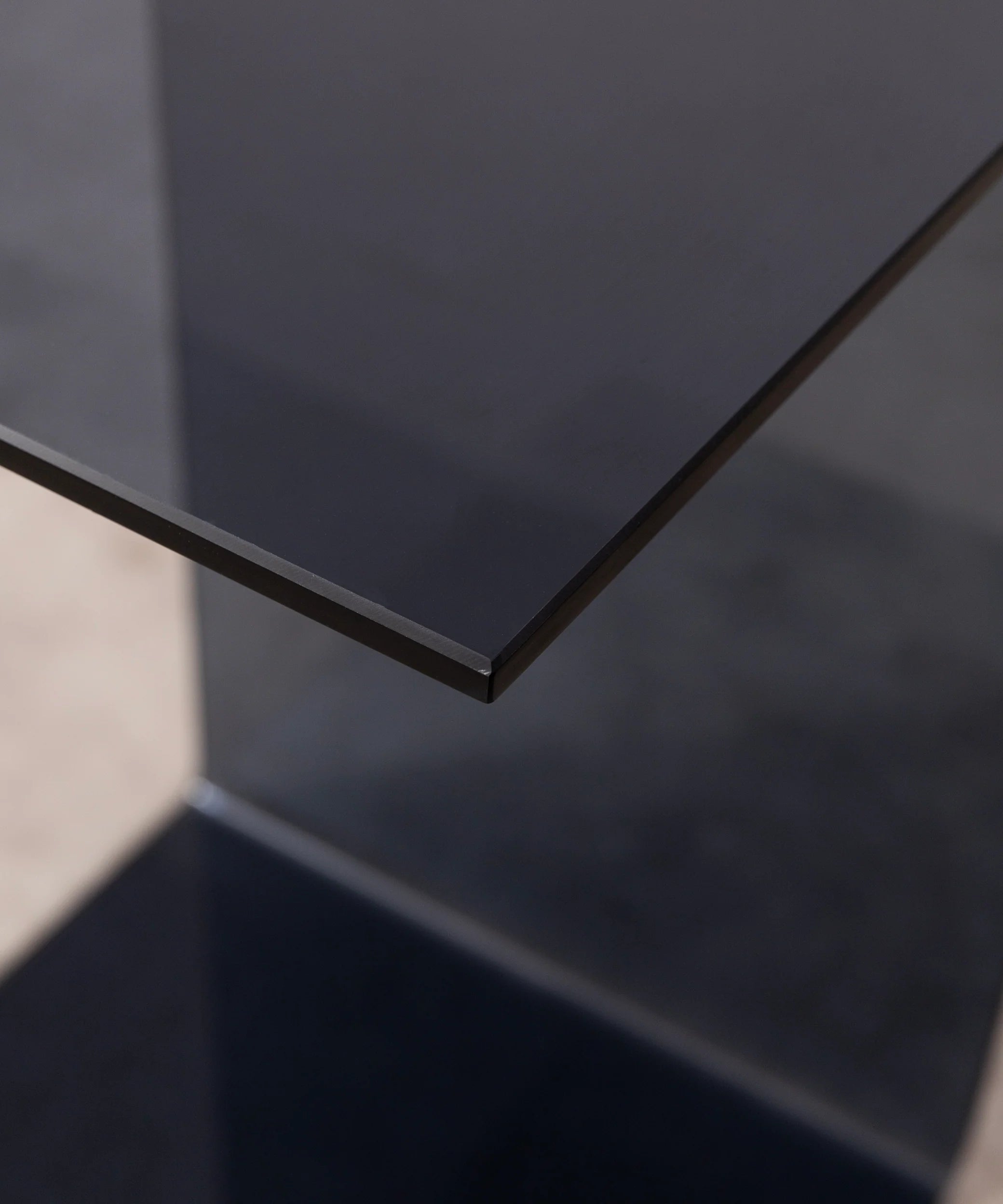 Close-up of the c-shaped side table in grey by vibehaus showcasing craftsmanship and material detail of designer couch table in acryl.