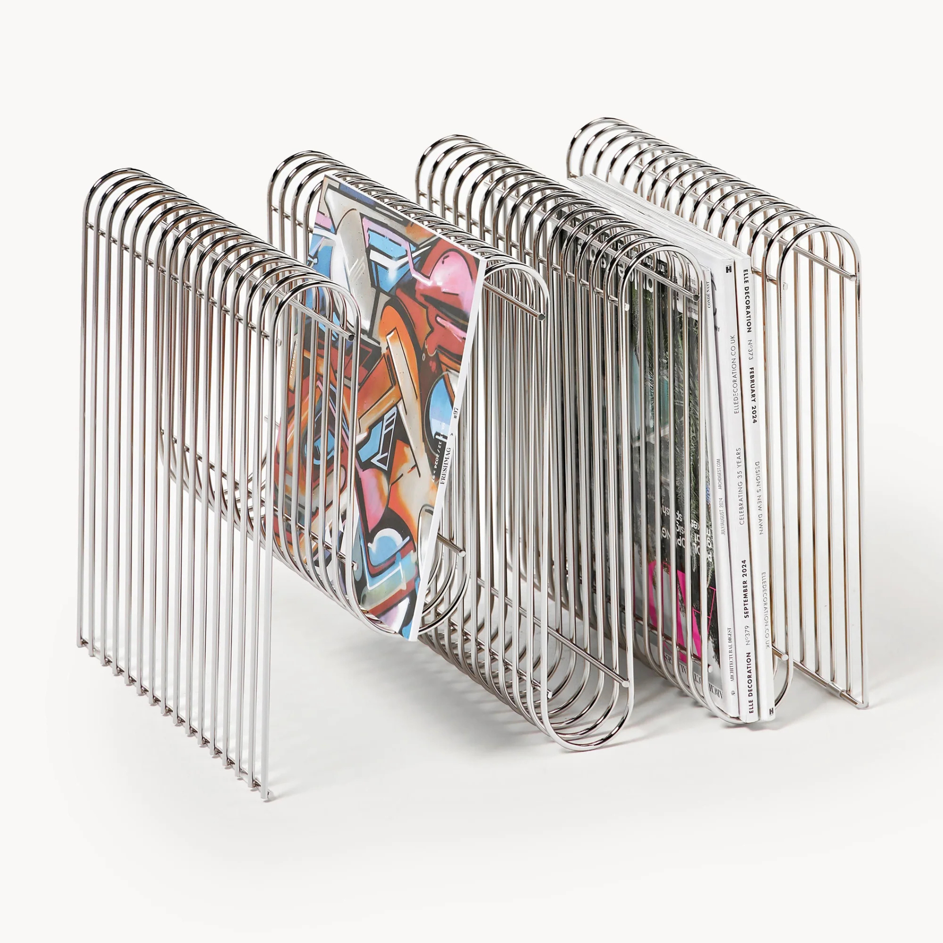 Chrome magazine rack holding colorful books on a white background