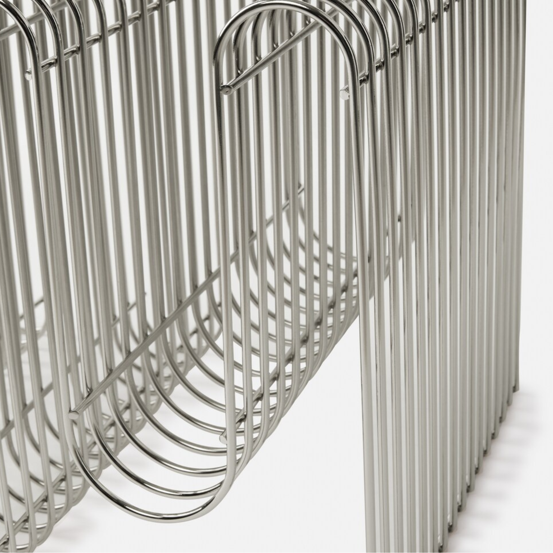 Chrome metal curved magazine holder on a white background