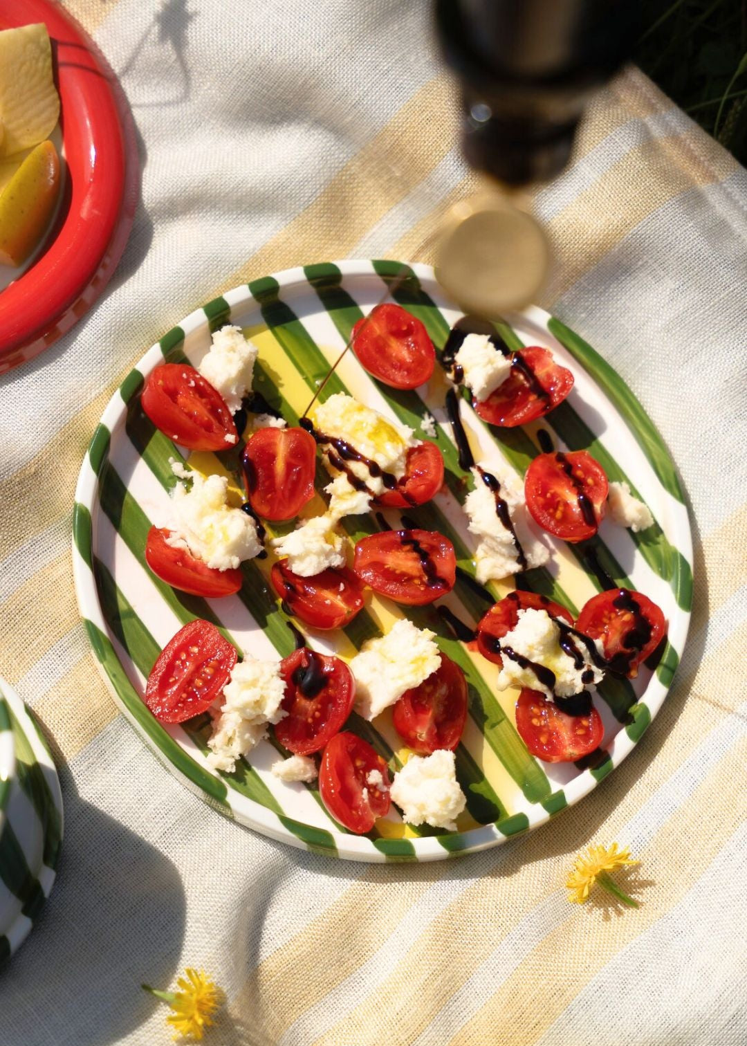 Plated salad with tomatoes and cheese on a Green-White striped artisan handmade ceramic dinner plate.