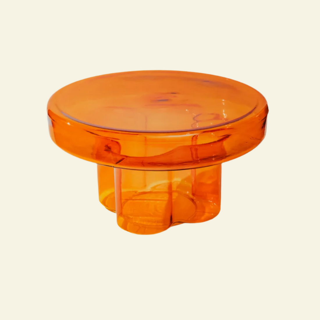 Amber glass side table with handblown round top and petal-inspired base in warm orange tone on beige background