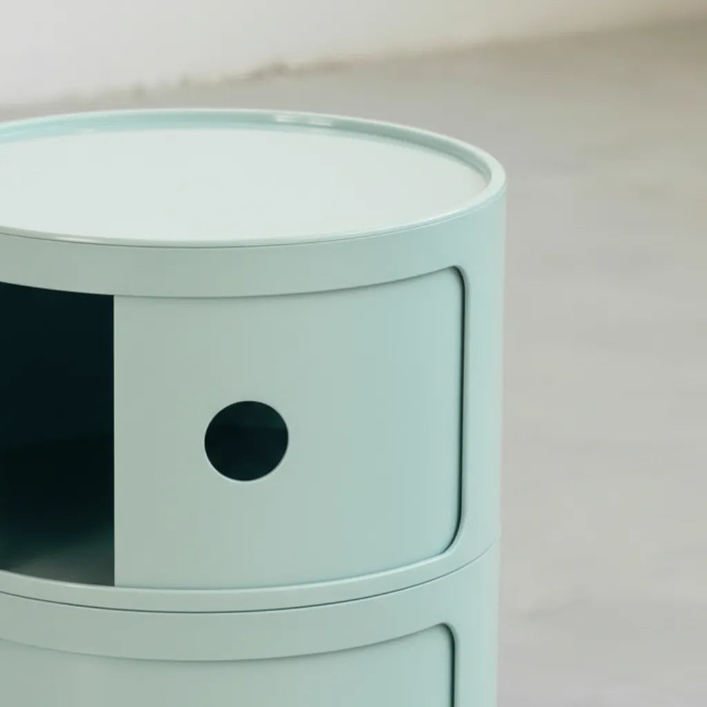 Close up of the Kartell Componibili dupe round modular storage unit in light blue glossy plastic with three tiers on concrete floor in white studio