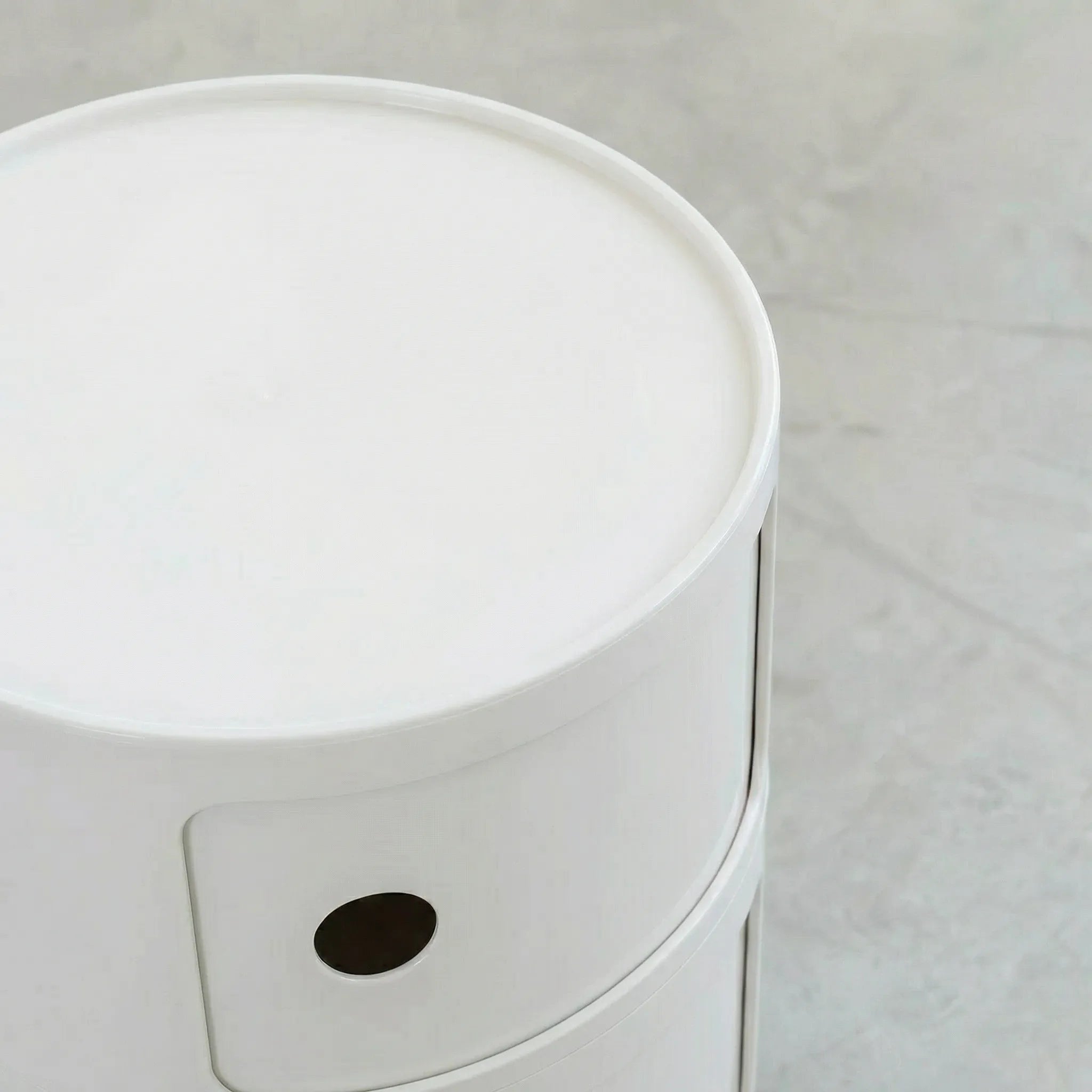 Close up of the Kartell Componibili dupe round modular storage unit in white glossy plastic with two tiers on concrete floor in white studio