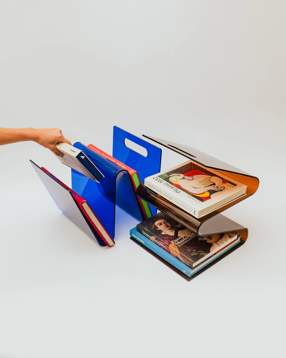 Colorful acrylic magazine, book in blue and amber rack holding books on a white surface