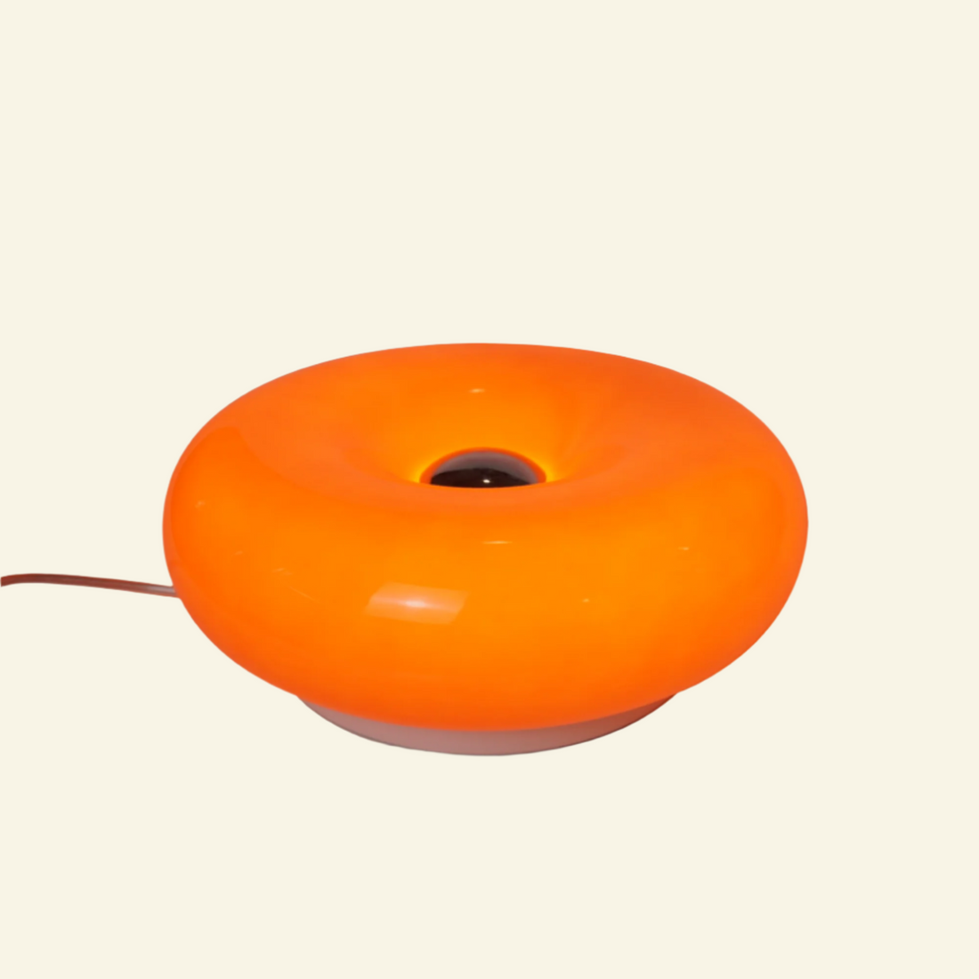 Modern orange table lamp with circular donut shape, built-in dimmable LED light, and sculptural form.
