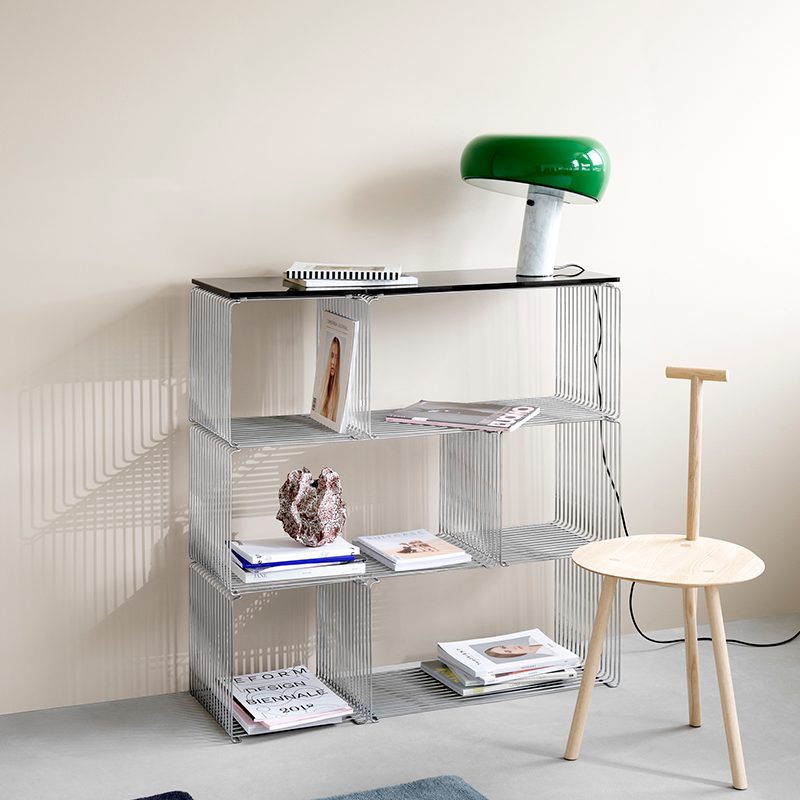 chrome wire cube modern metal shelving unit with books and decor items against a neutral wall.