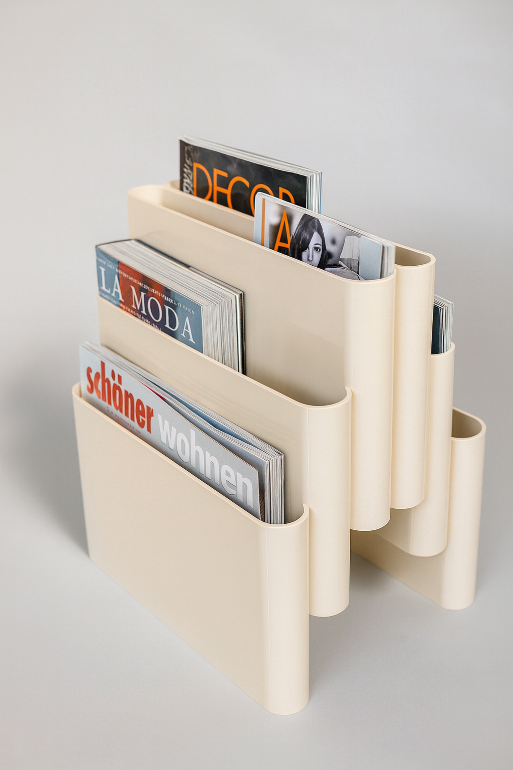 Beige magazine cascade rack holder with various magazines on a light gray background