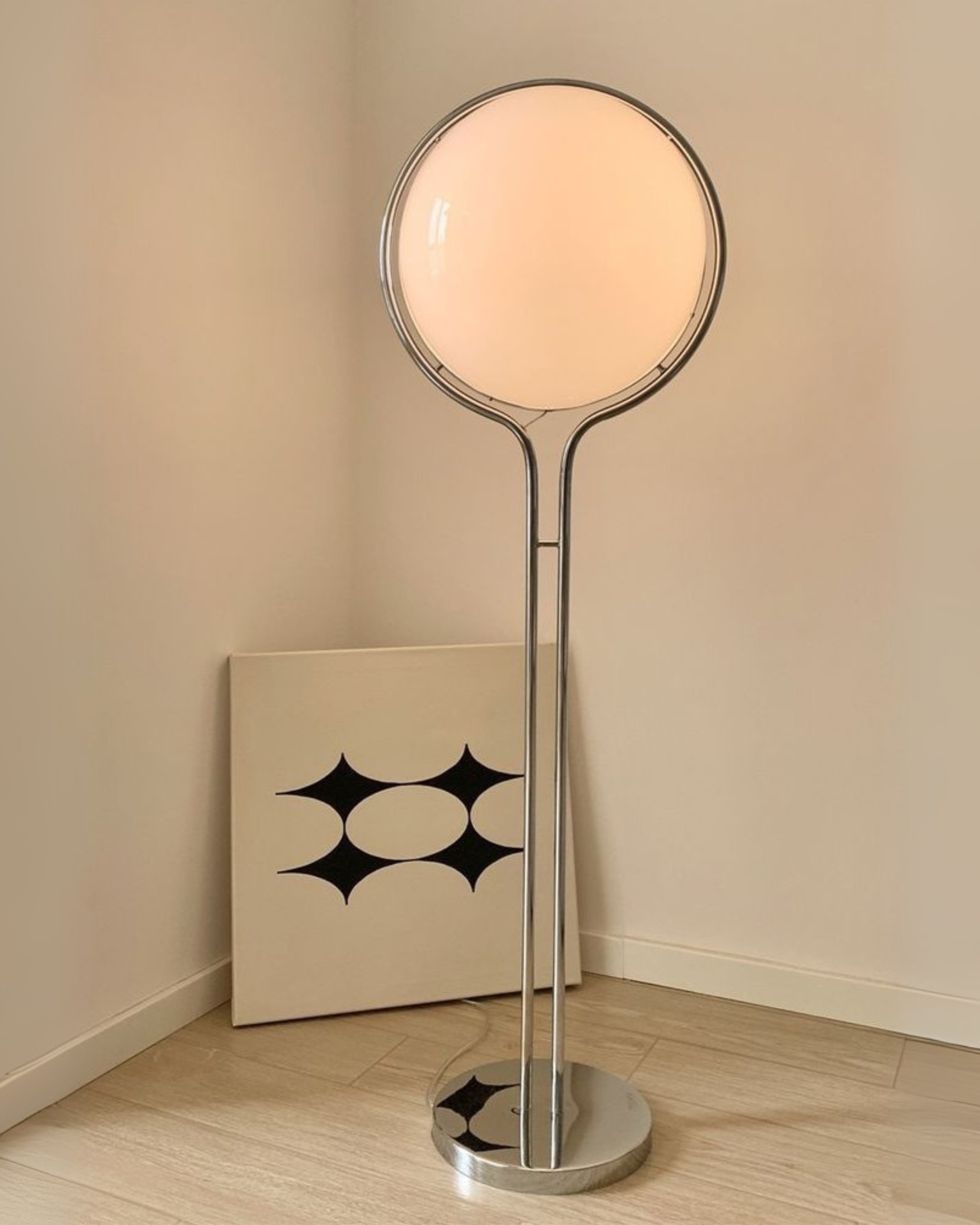 Moderne vintage globus gulvlampe med en rund glasskærm i et minimalistisk rum.