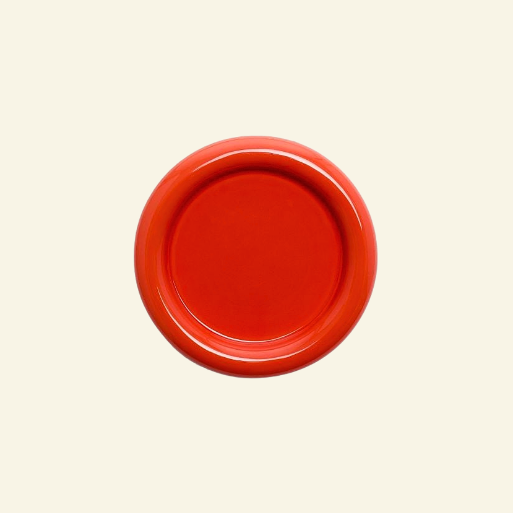 Red round chunky ceramic plate on a beige background