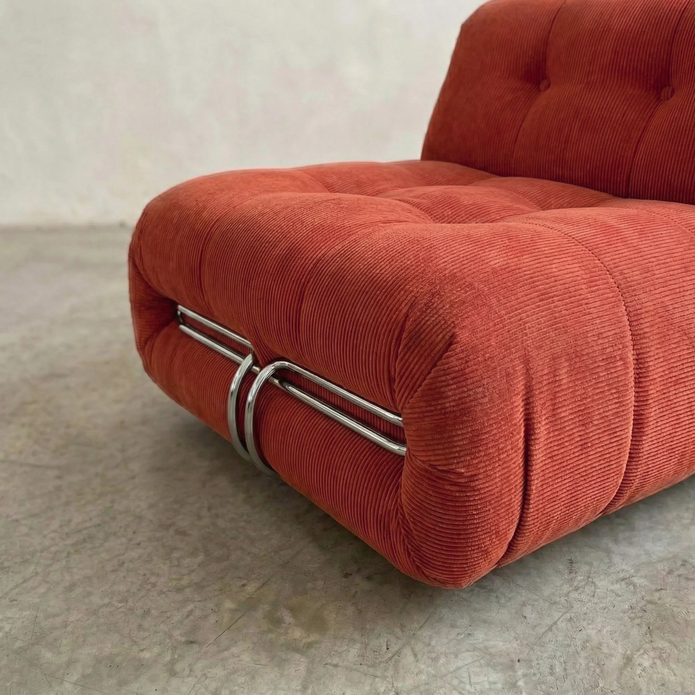 soriana chair dupe in terracotta corduroy angled view on gray floor with white wall background