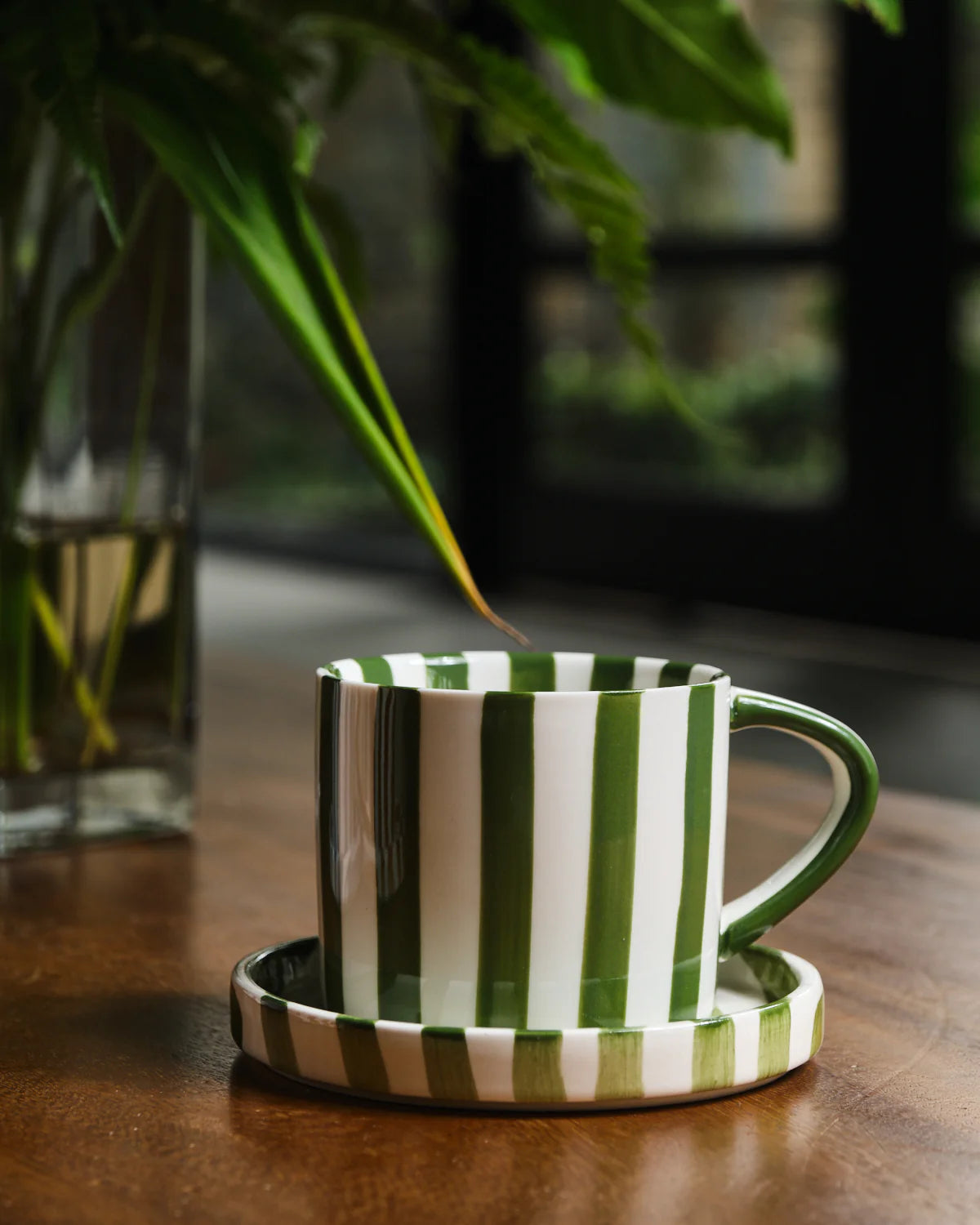 Green and white striped ceramic mug with matching coaster on a wooden surface