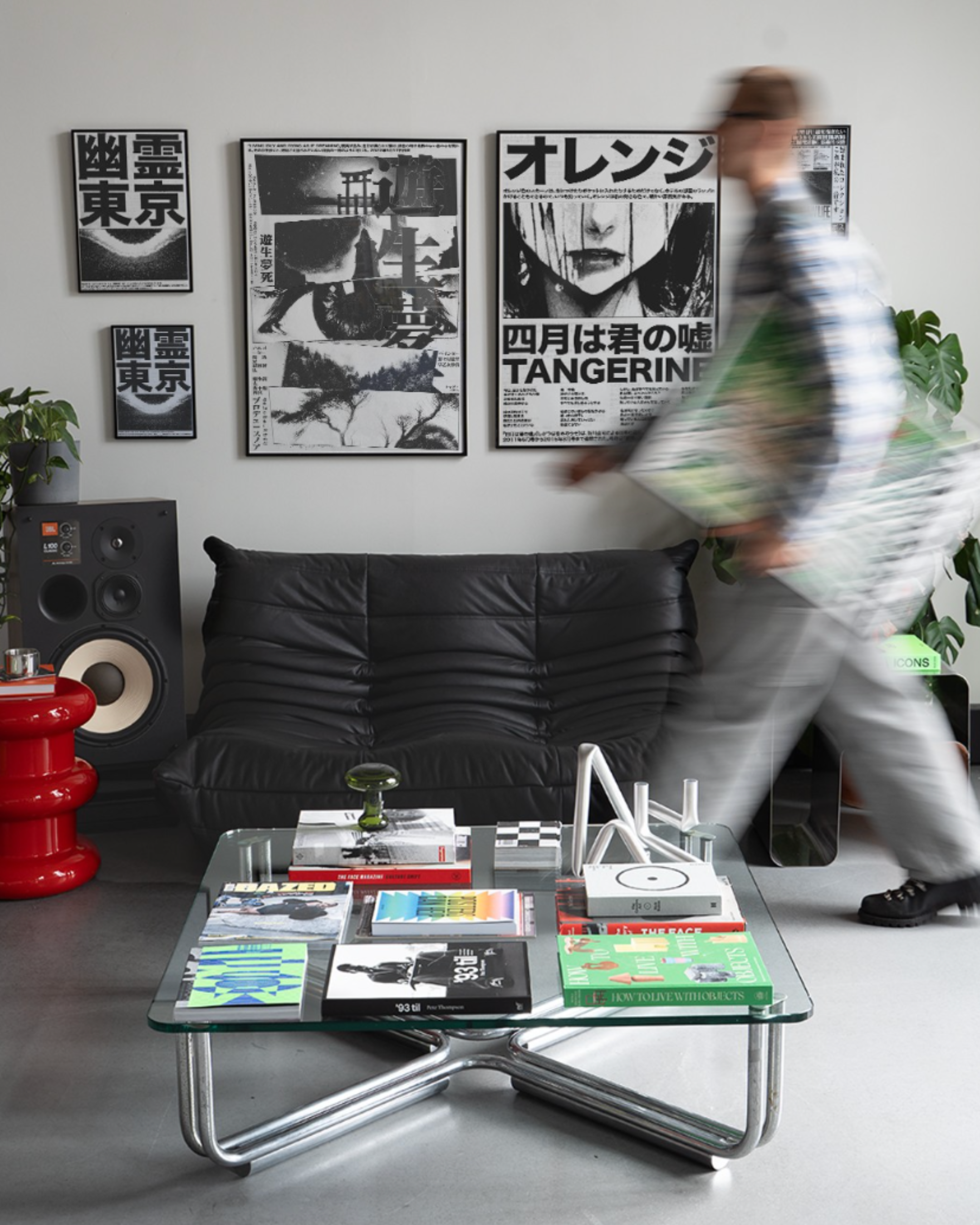 Modern living room with a glass coffee table, Togo black leather 2-seater replica sofa, and wall art.