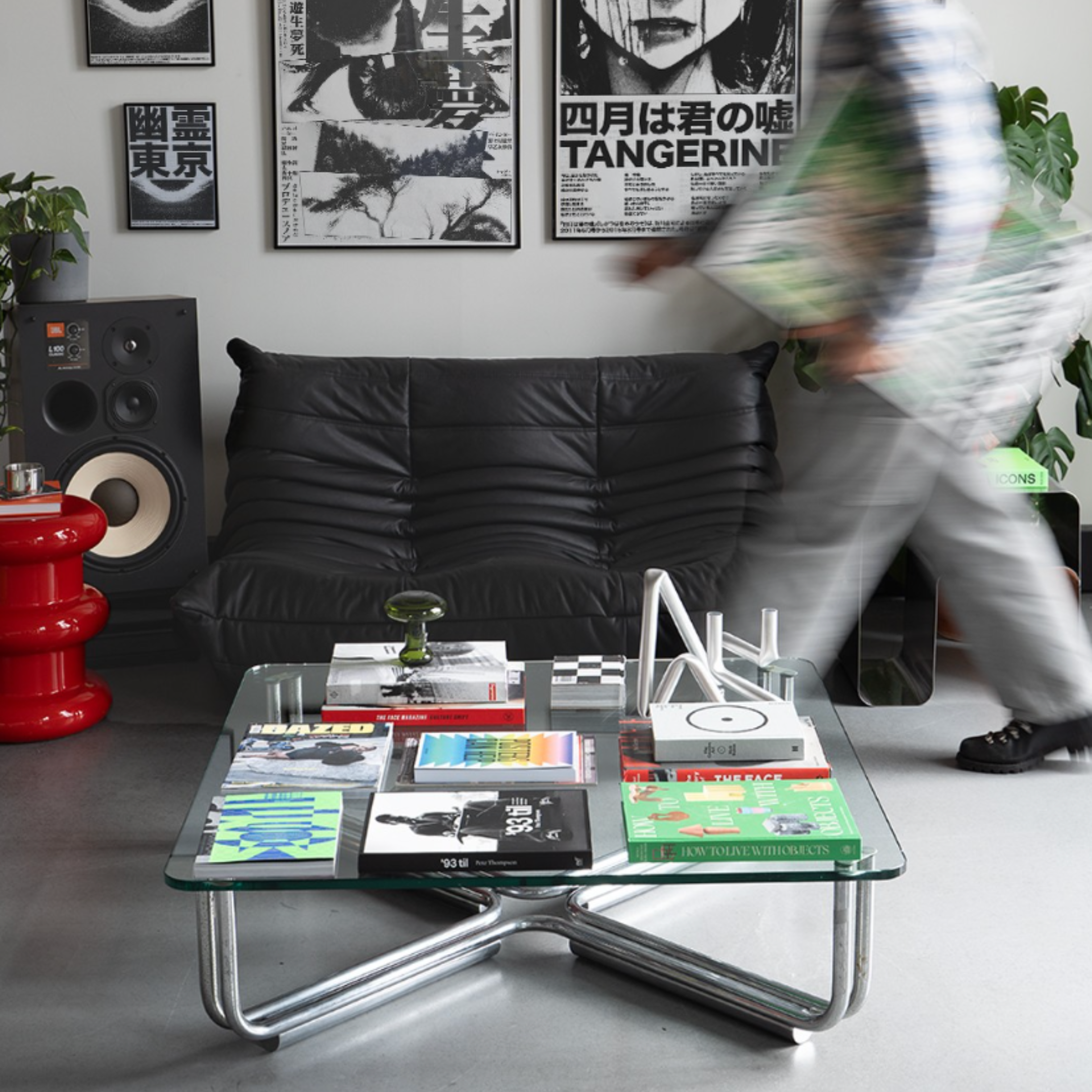 Modern living room with a glass coffee table, Togo black leather 2-seater replica sofa, and wall art.