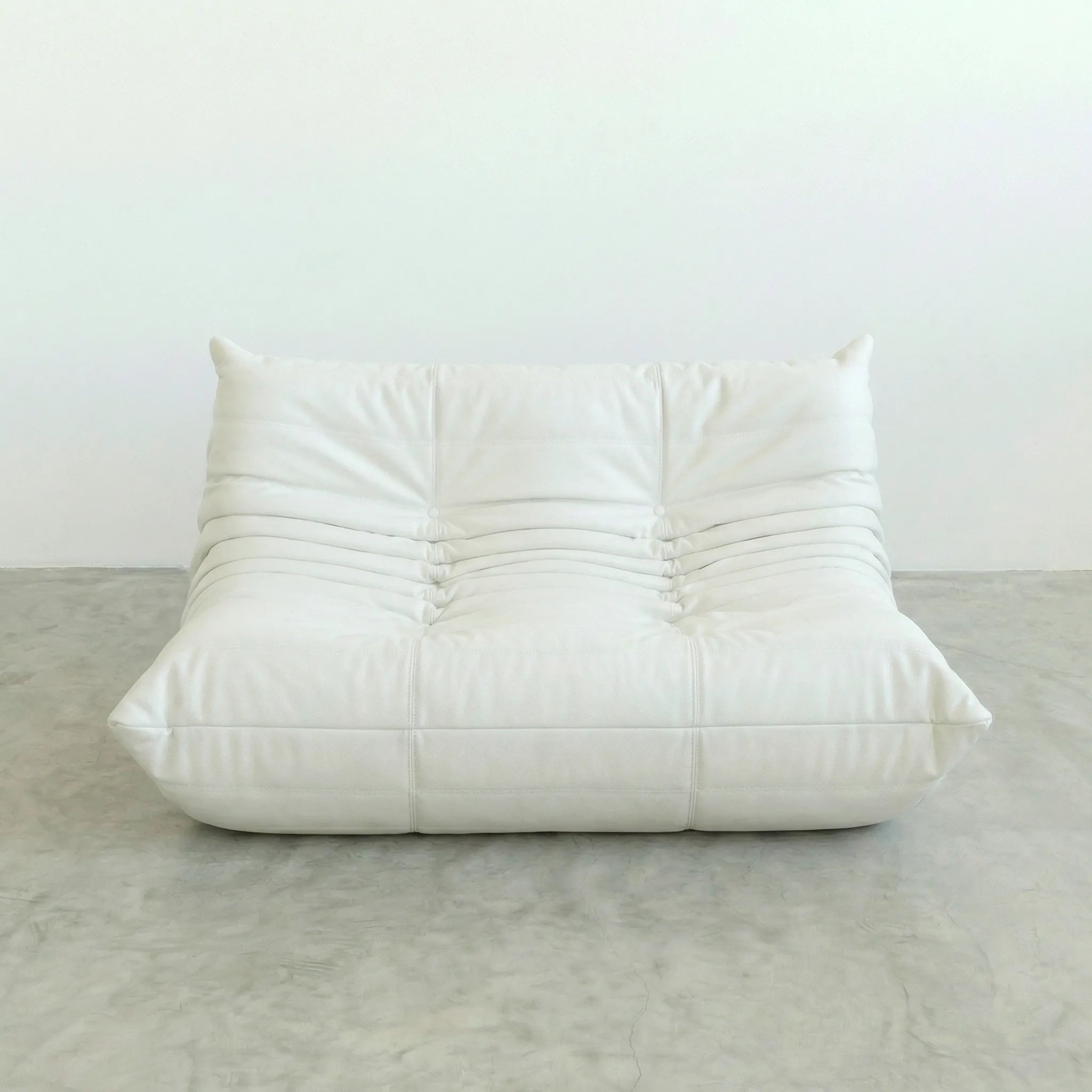 White togo leather sofa dupe on a gray floor with a white wall background