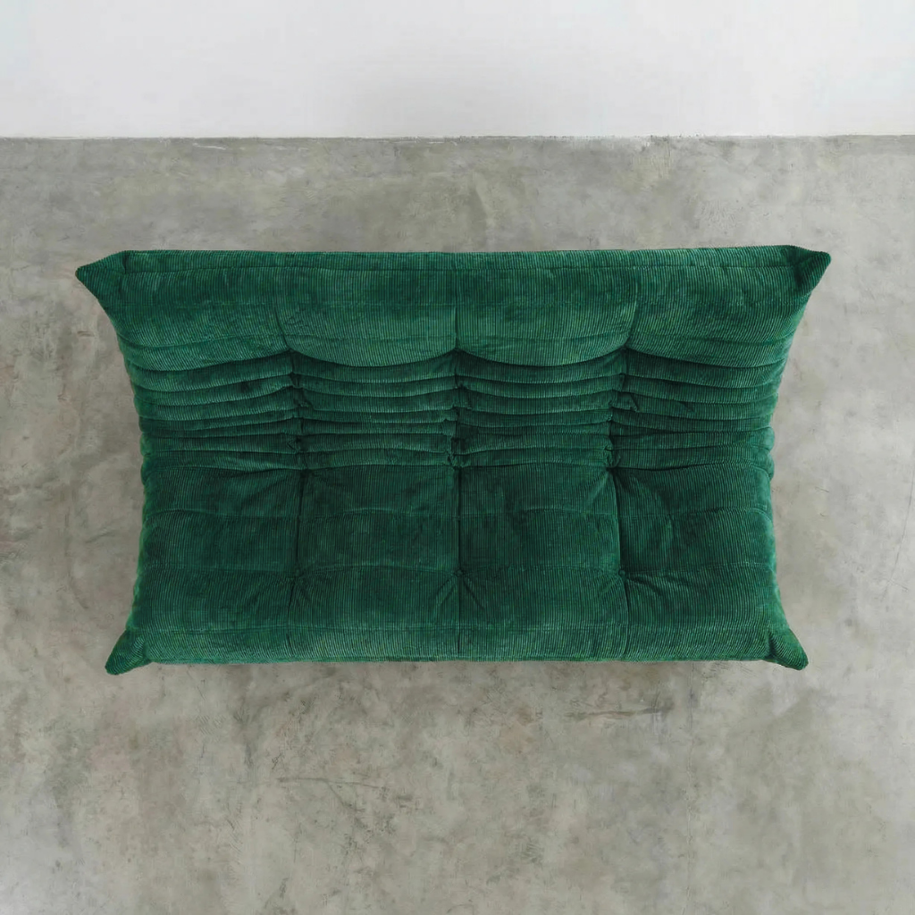 Bruma 3 seater sofa in dark green Corduroy by vibehaus on a concrete floor, photographed from a top angle.