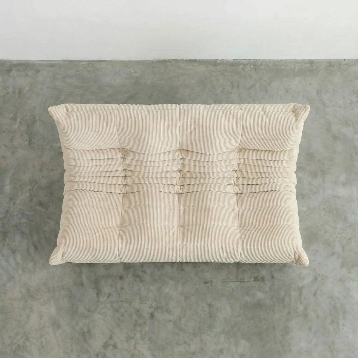Bruma 3 seater sofa in cream Corduroy by vibehaus on a concrete floor, photographed from a top angle.