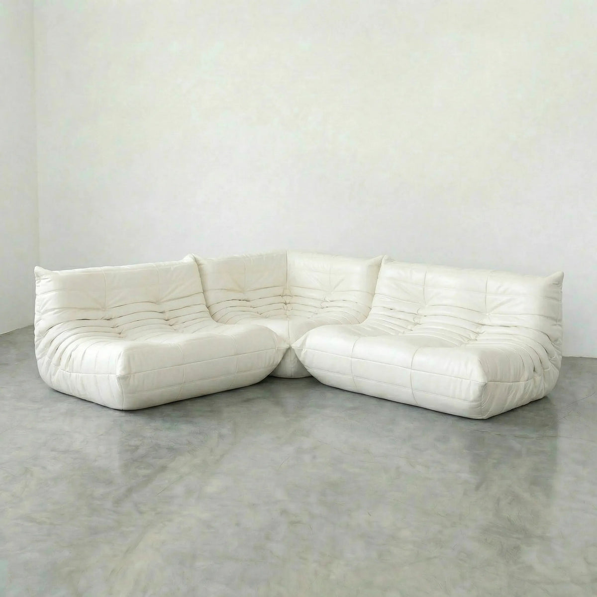 White leather Bruma sectional sofa on a concrete floor with a white wall background