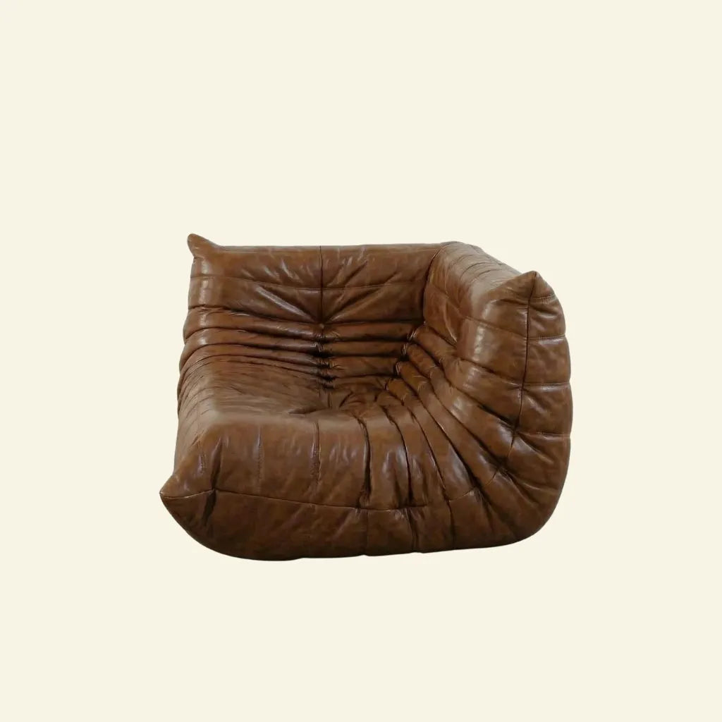 Bruma Corner Section in brown leather on a concrete floor with a white wall background