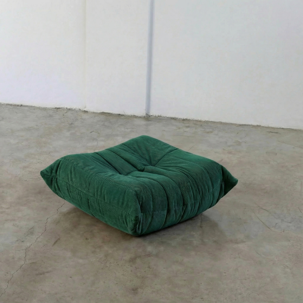 Dark Green Bruma-styled ottoman in corduroy by vibehaus on a concrete floor with white walls