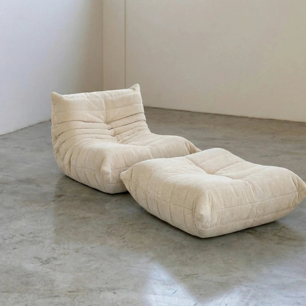 Bruma chair and ottoman in Cream Corduroy by Vibehaus on a concrete floor