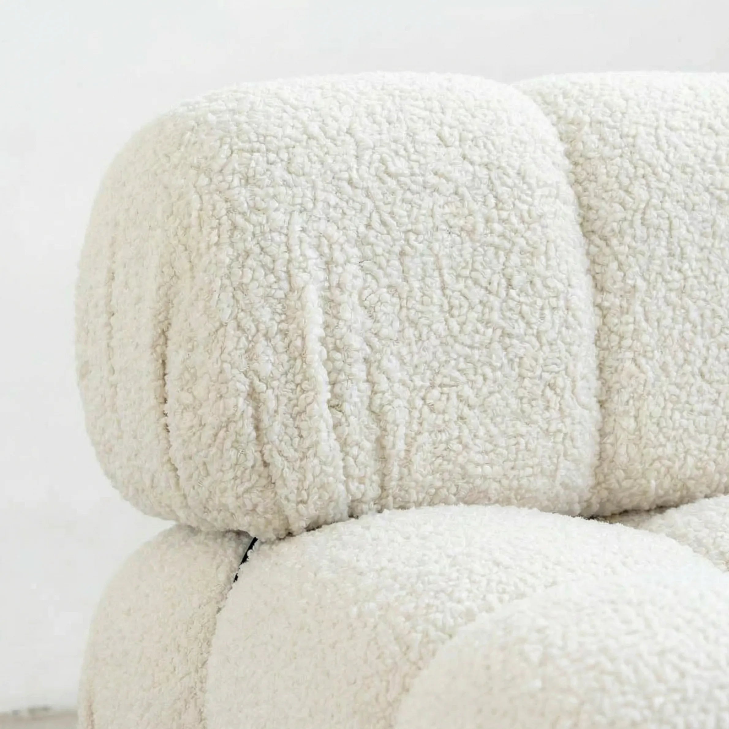 Close-up of the camaleonda armchair dupe with left artmrest in white bouclé with a neutral background