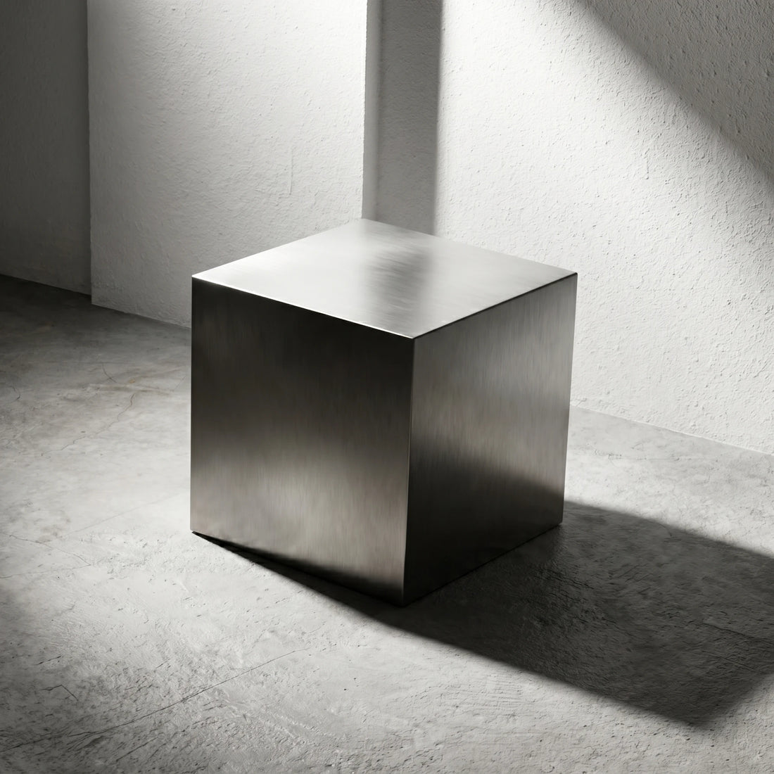 Chrome Steel Cube Table in brushed stainless steel, shown as a sculptural side table on a concrete floor.