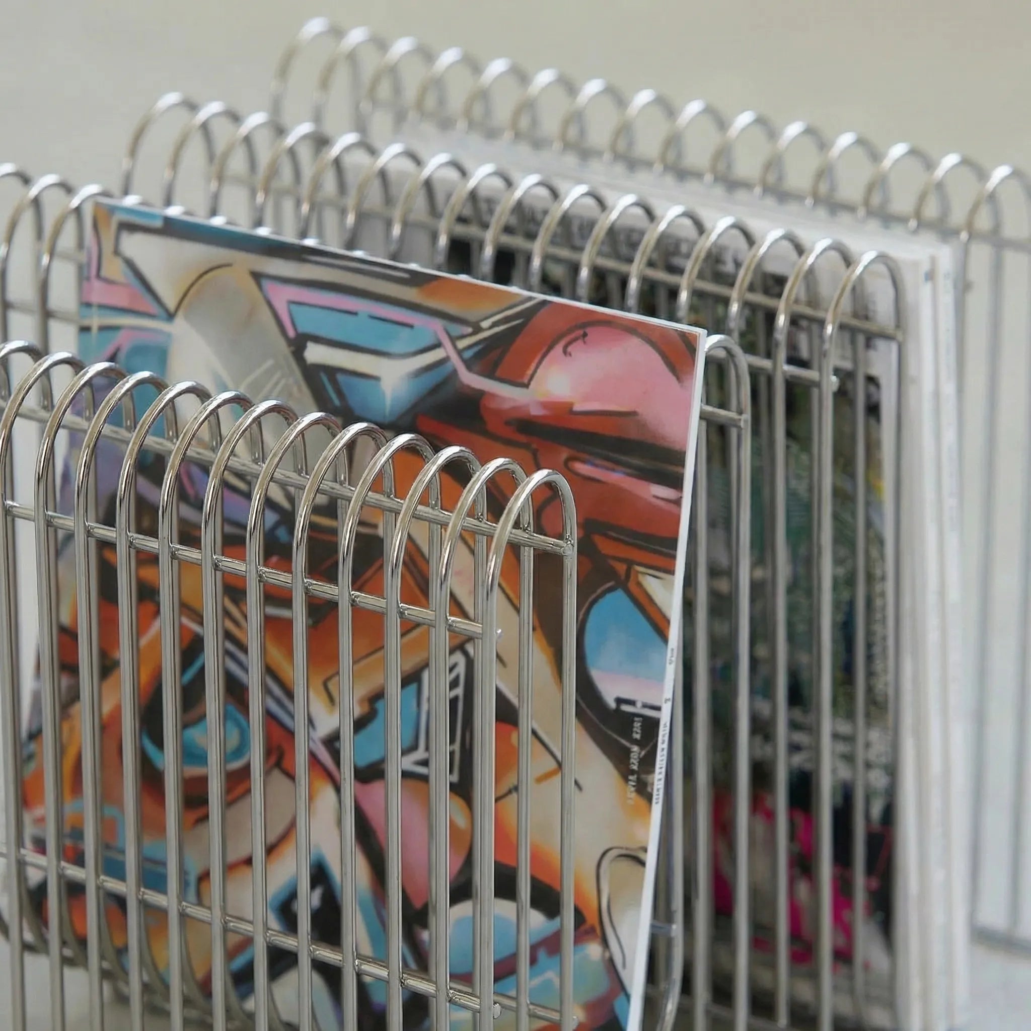 Chrome magazine holder with curved metal frame