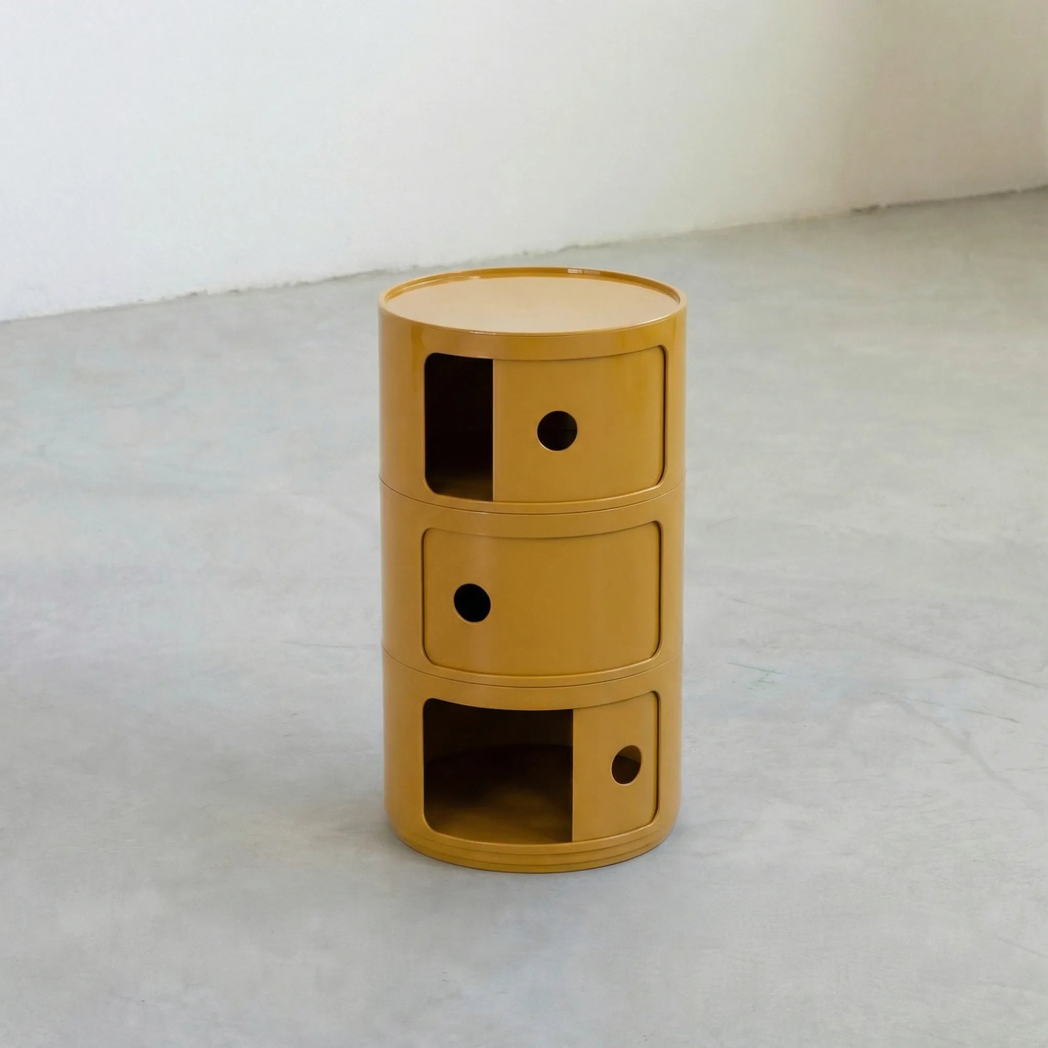 Mustard Yellow glossy round modular storage unit, Kartell Componibili dupe with three tiers in minimalist concrete studio