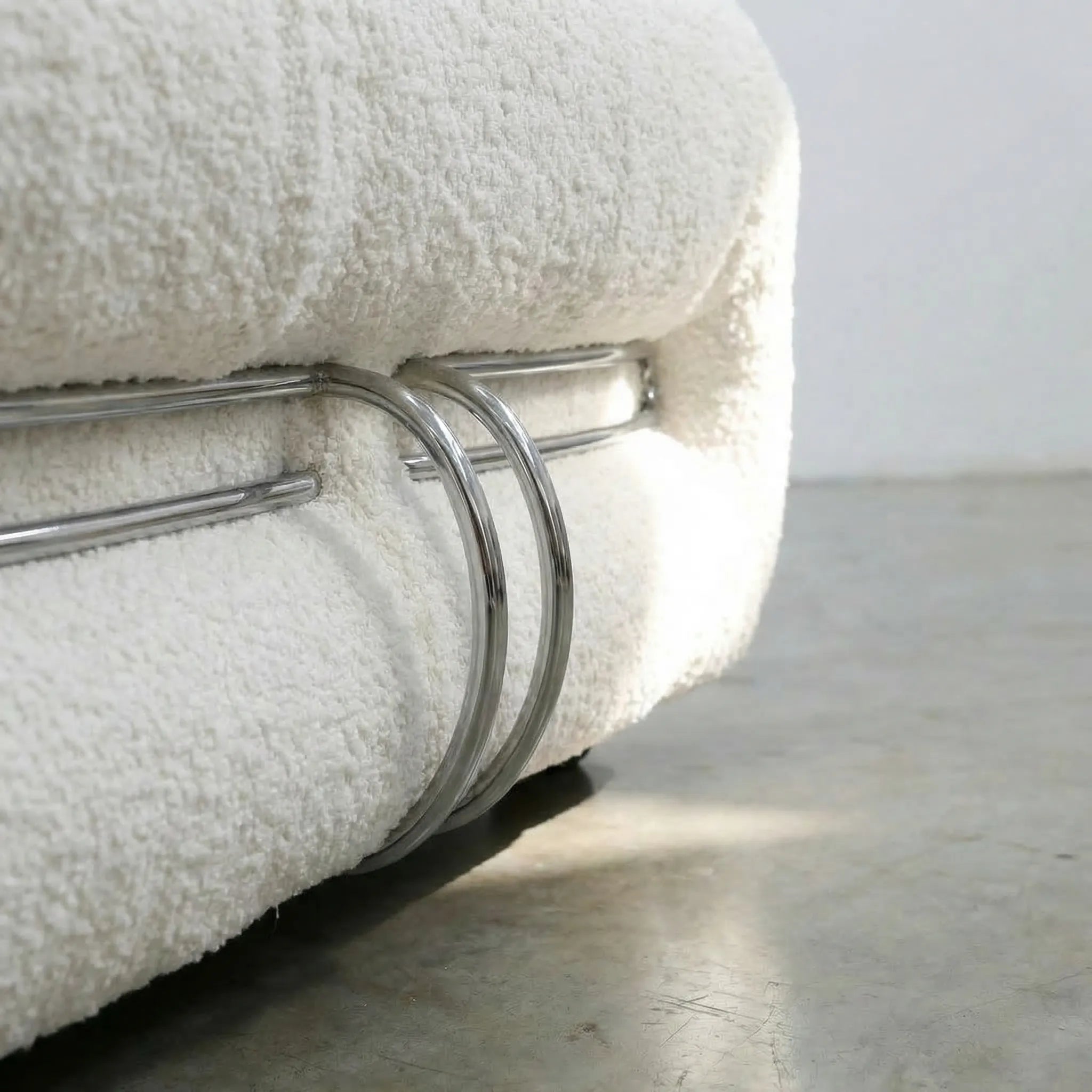 Close-up of a Soriana Chair Dupe in white boucle with a metal rack on a light gray surface.
