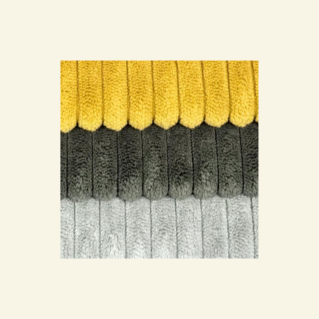 Close-up of textured corduroy fabric with yellow, gray, and white stripes on a beige background