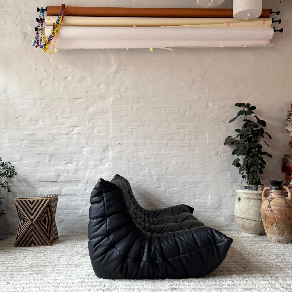 Togo 3-seater sofa replica in black leather styled in a modern living room with rug and plants – Vibehaus.