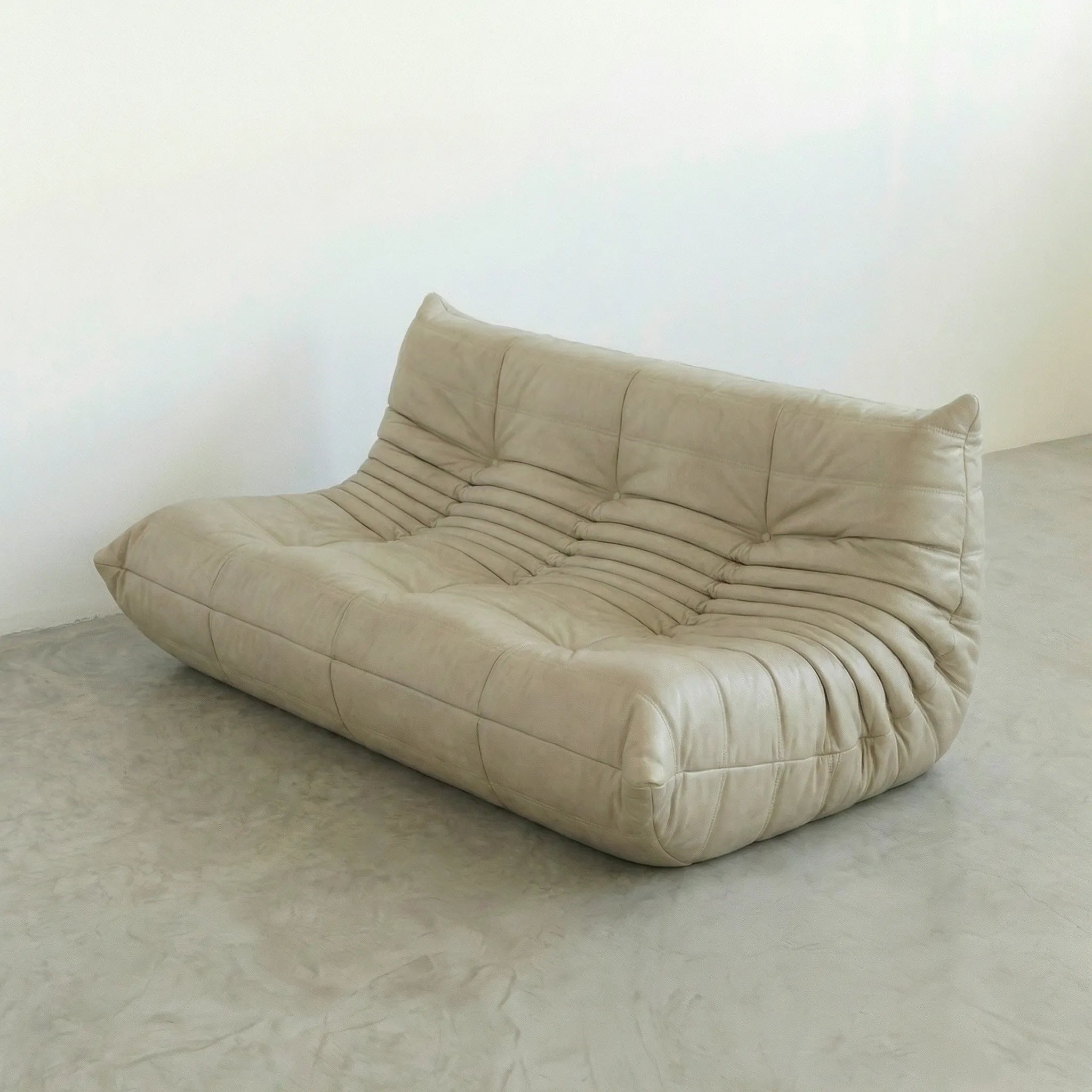 Beige leather 3-seater togo sofa dupe on a gray floor with a white wall background