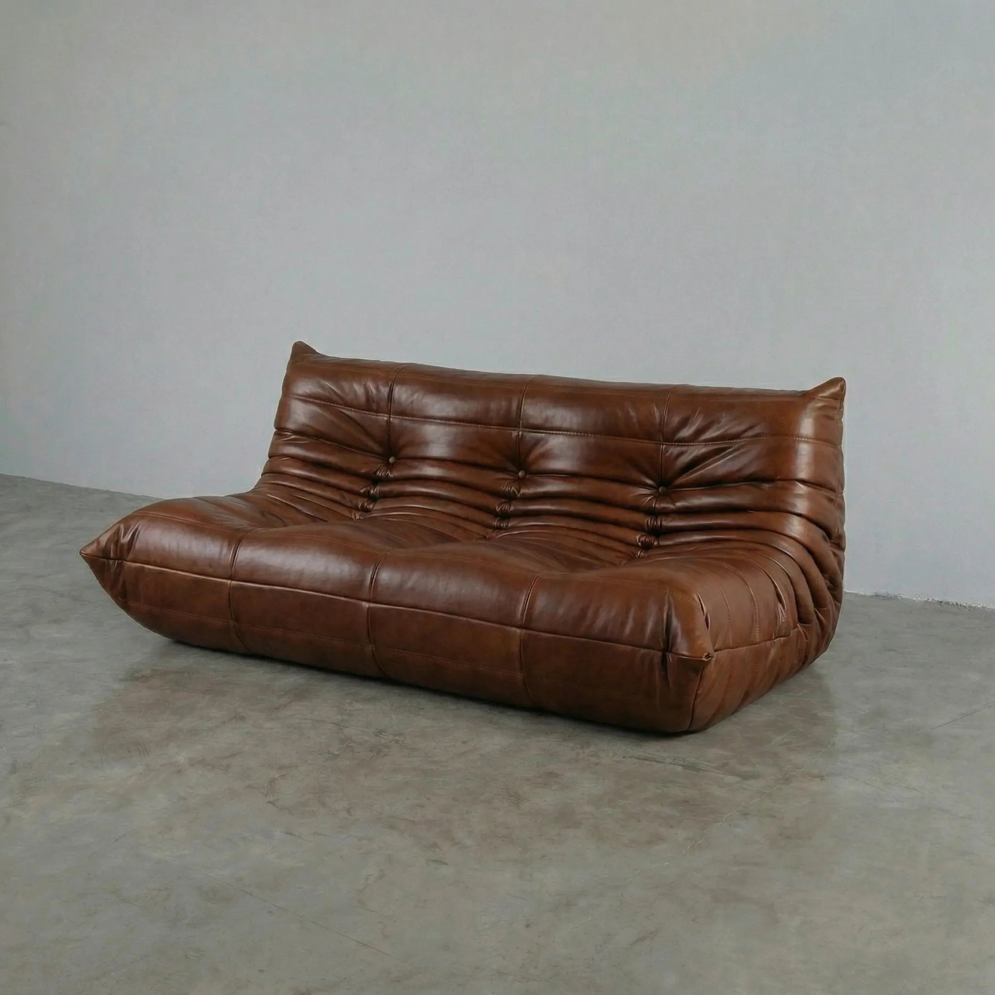 Brown leather 3-seater sofa dupe on a gray floor with a plain white wall background