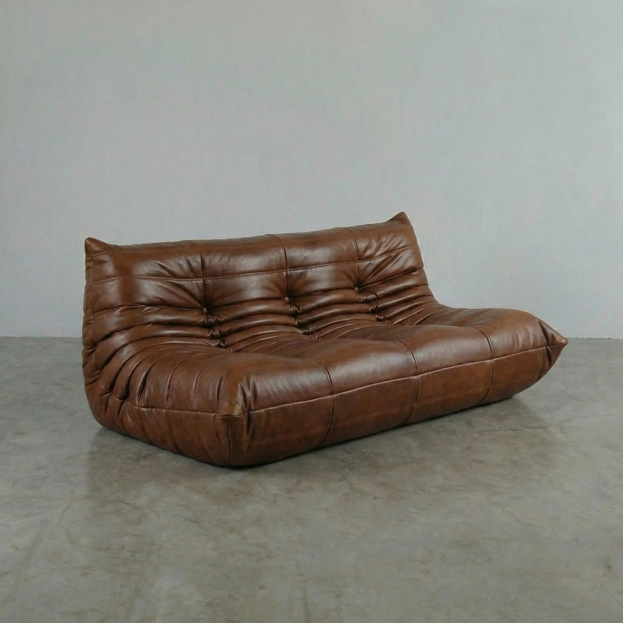 Brown leather 3-seater sofa dupe on a gray floor with a plain white wall background