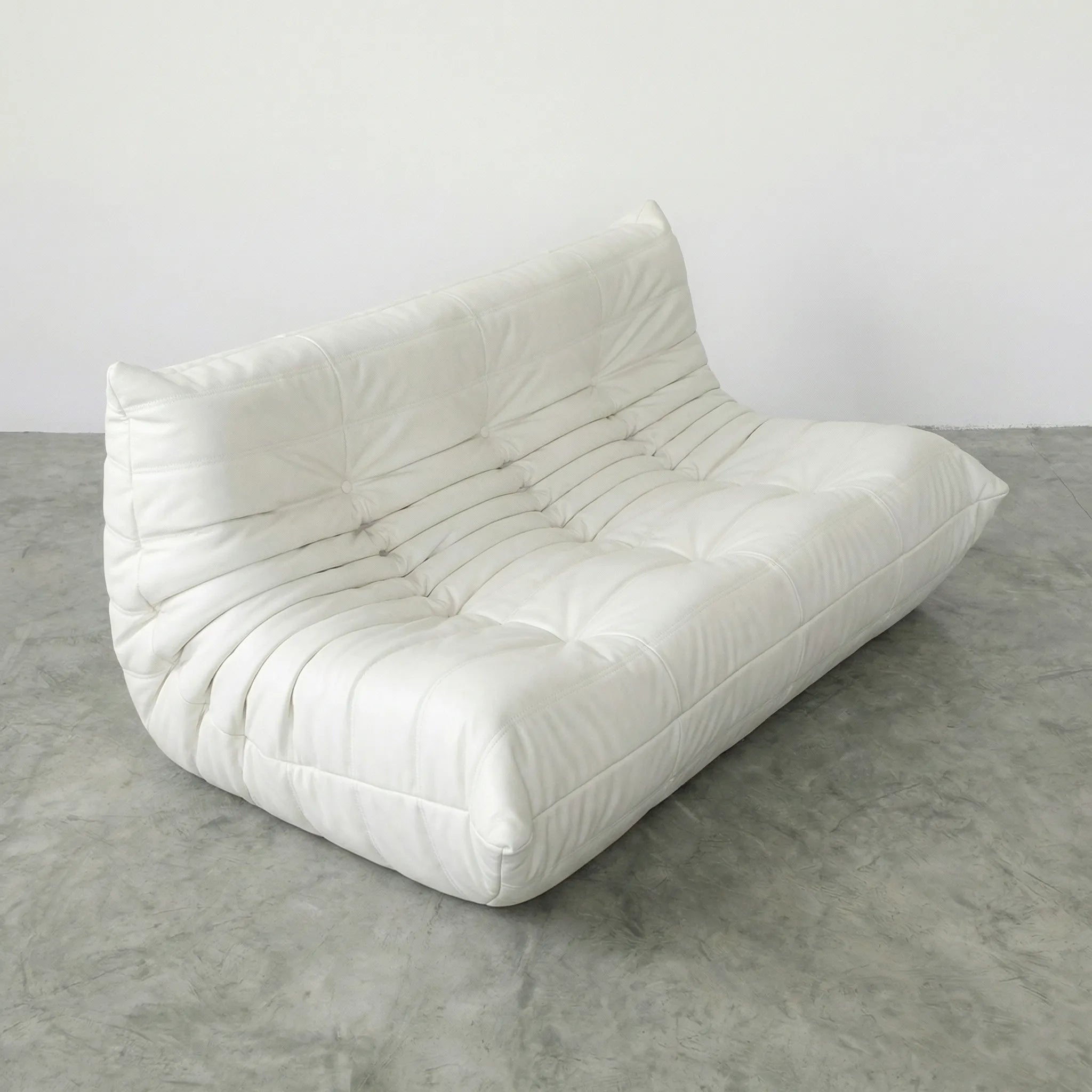 White 3-seater togo sofa dupe in leather on a concrete floor