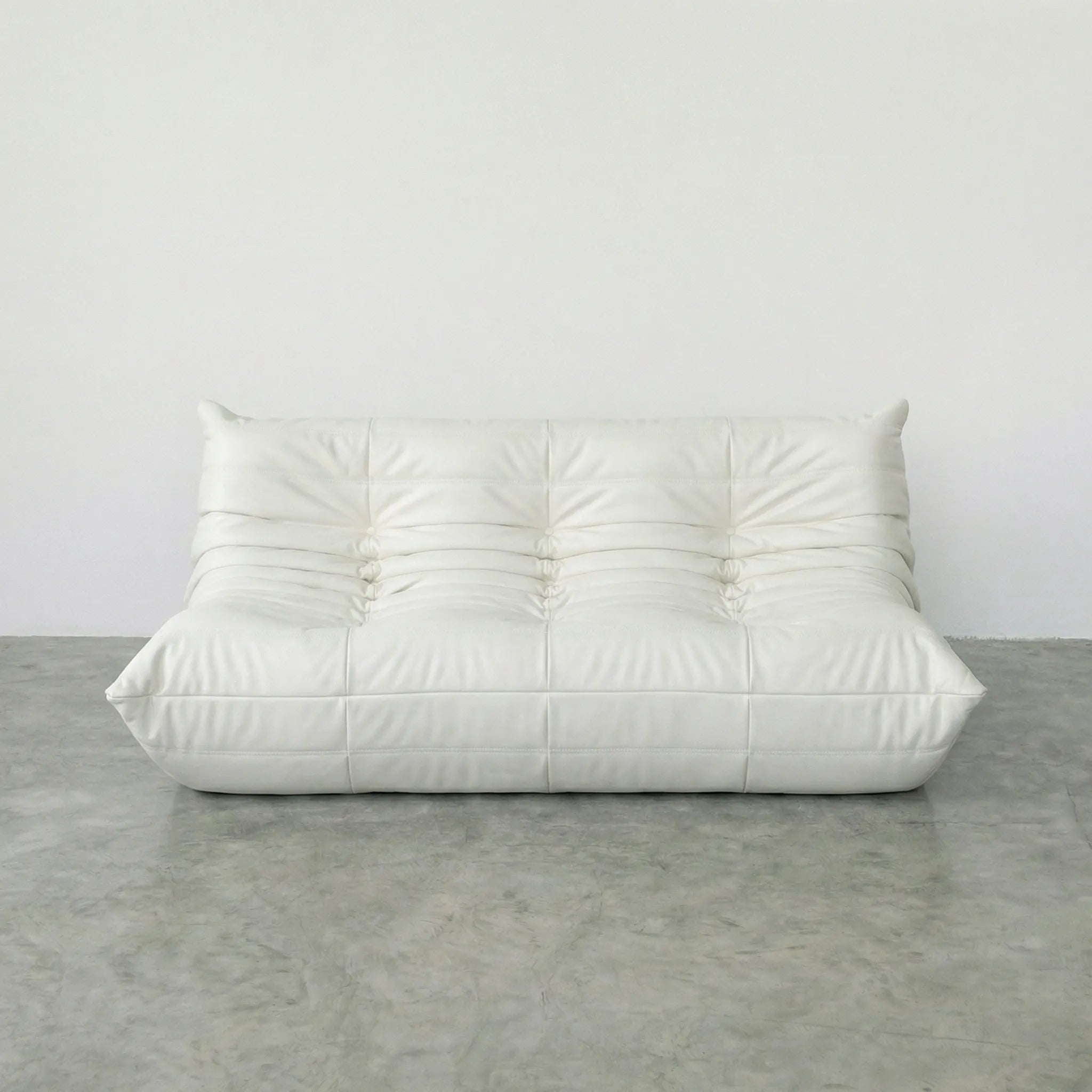 White 3-seater togo sofa dupe in leather on a concrete floor