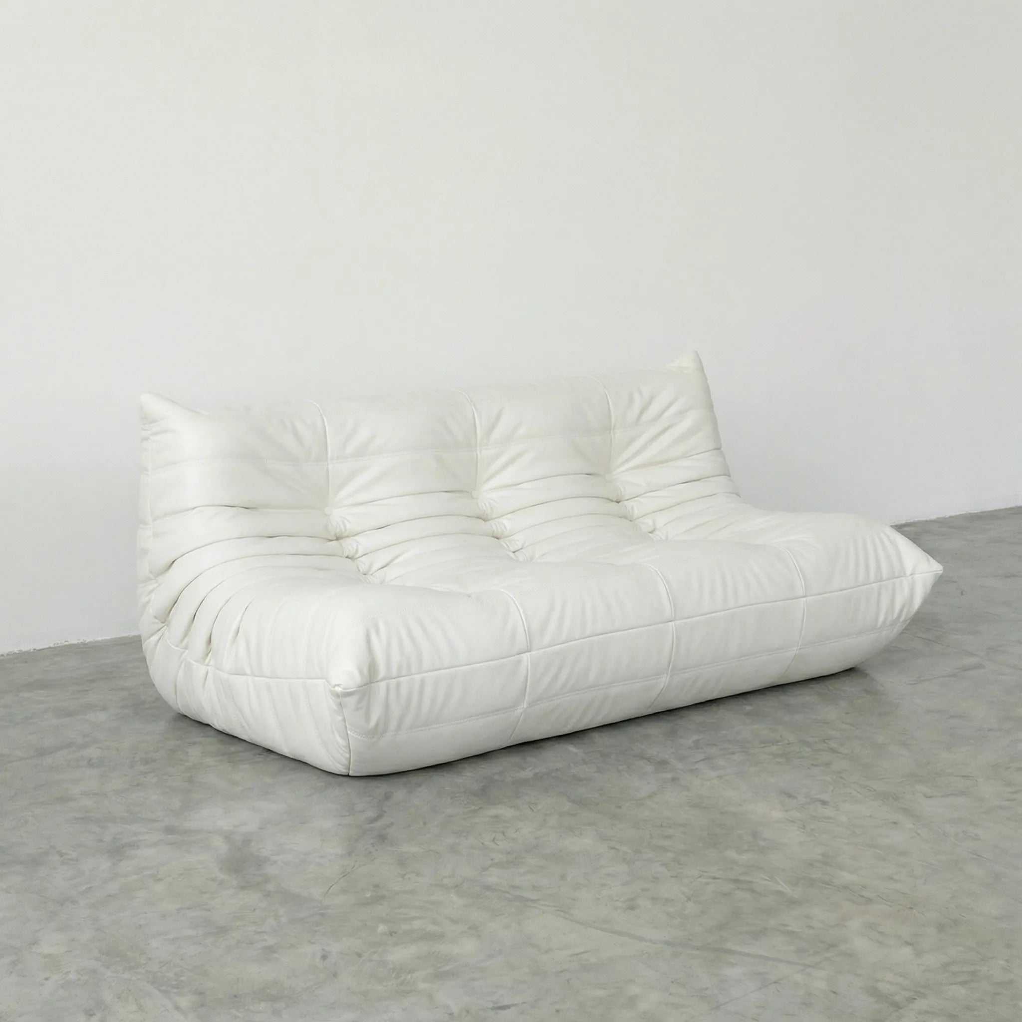White 3-seater togo sofa dupe in leather on a concrete floor