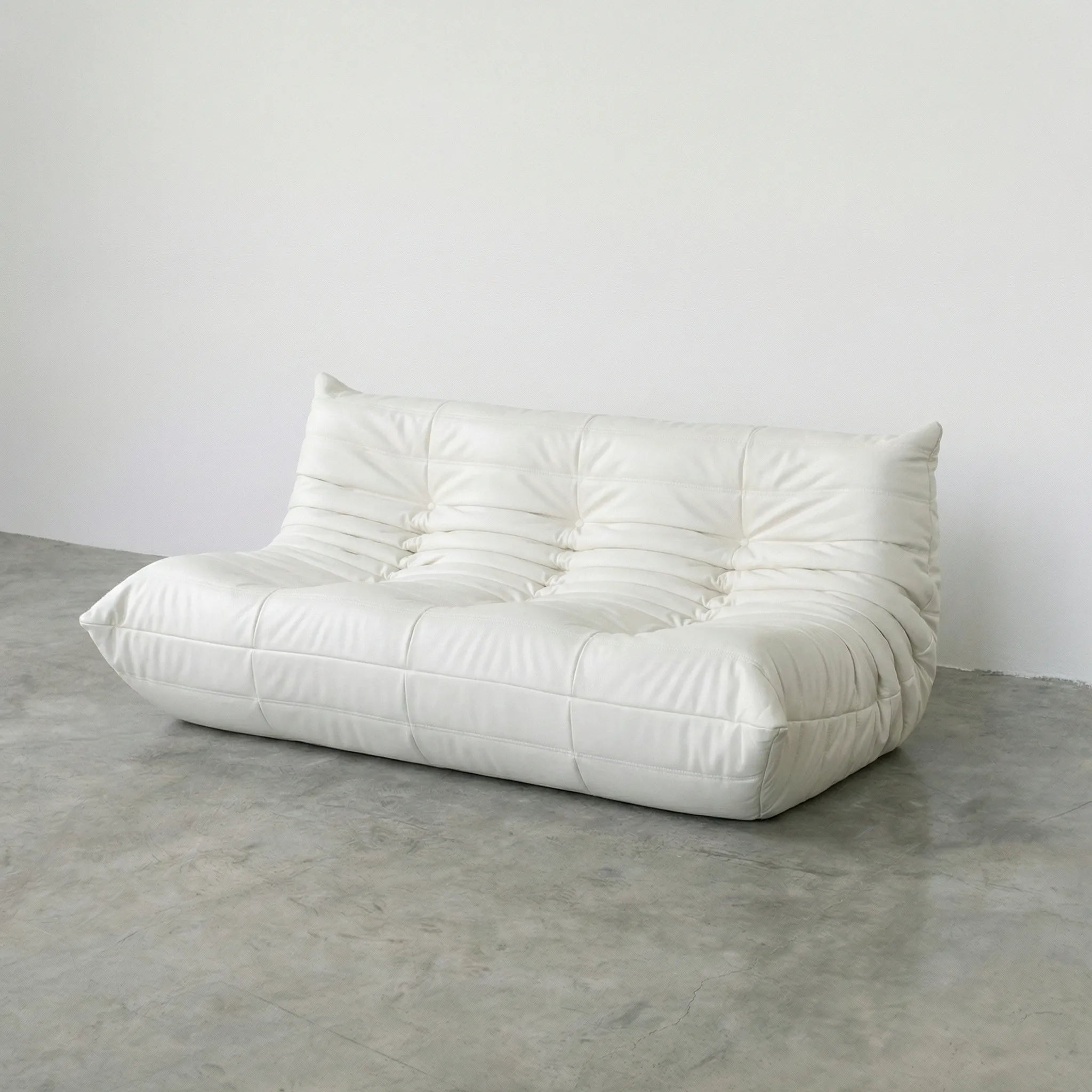 White 3-seater togo sofa dupe in leather on a concrete floor