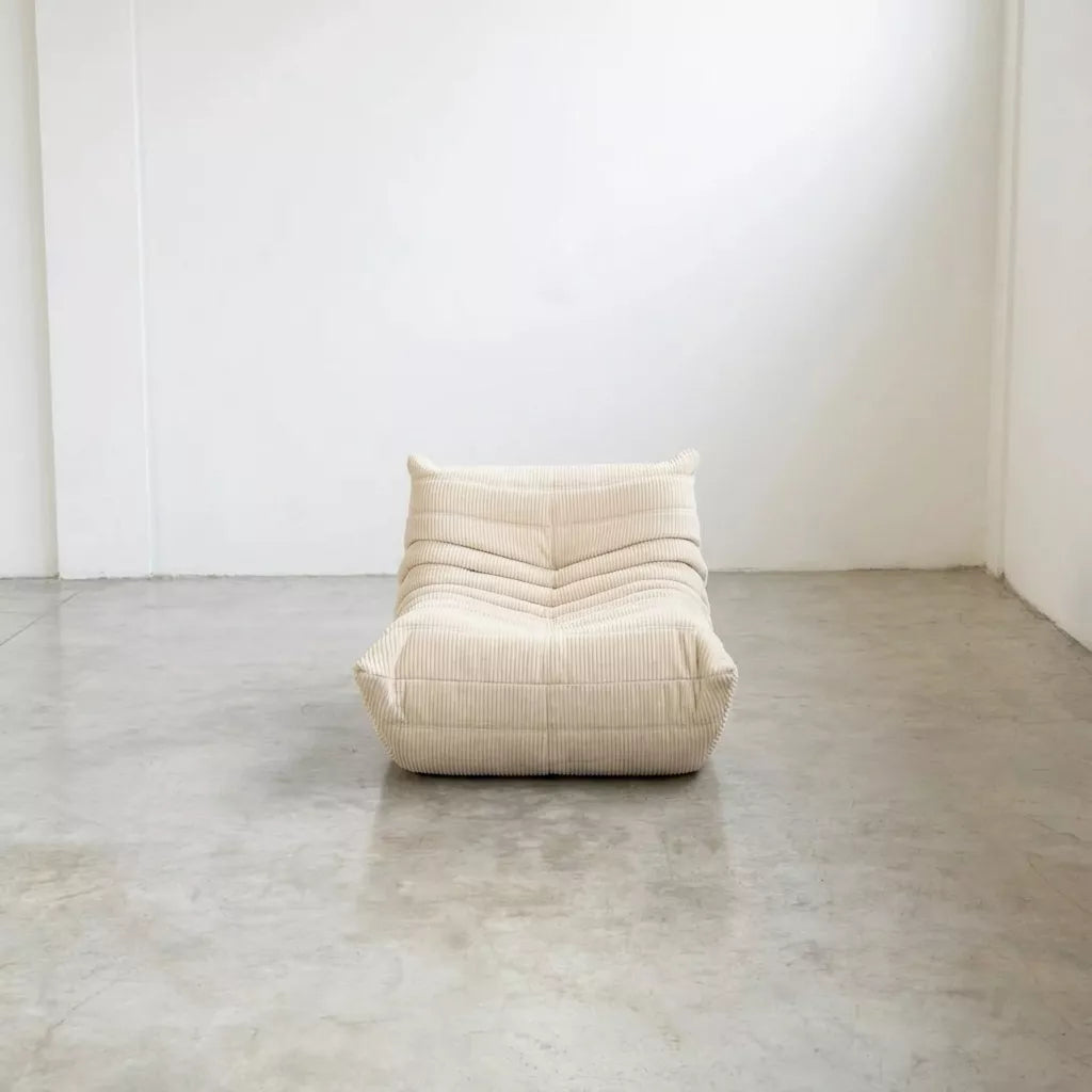 Dupe of the cream corduroy Togo-chair by michael ducaroy– low, frameless design with plush channel tufting