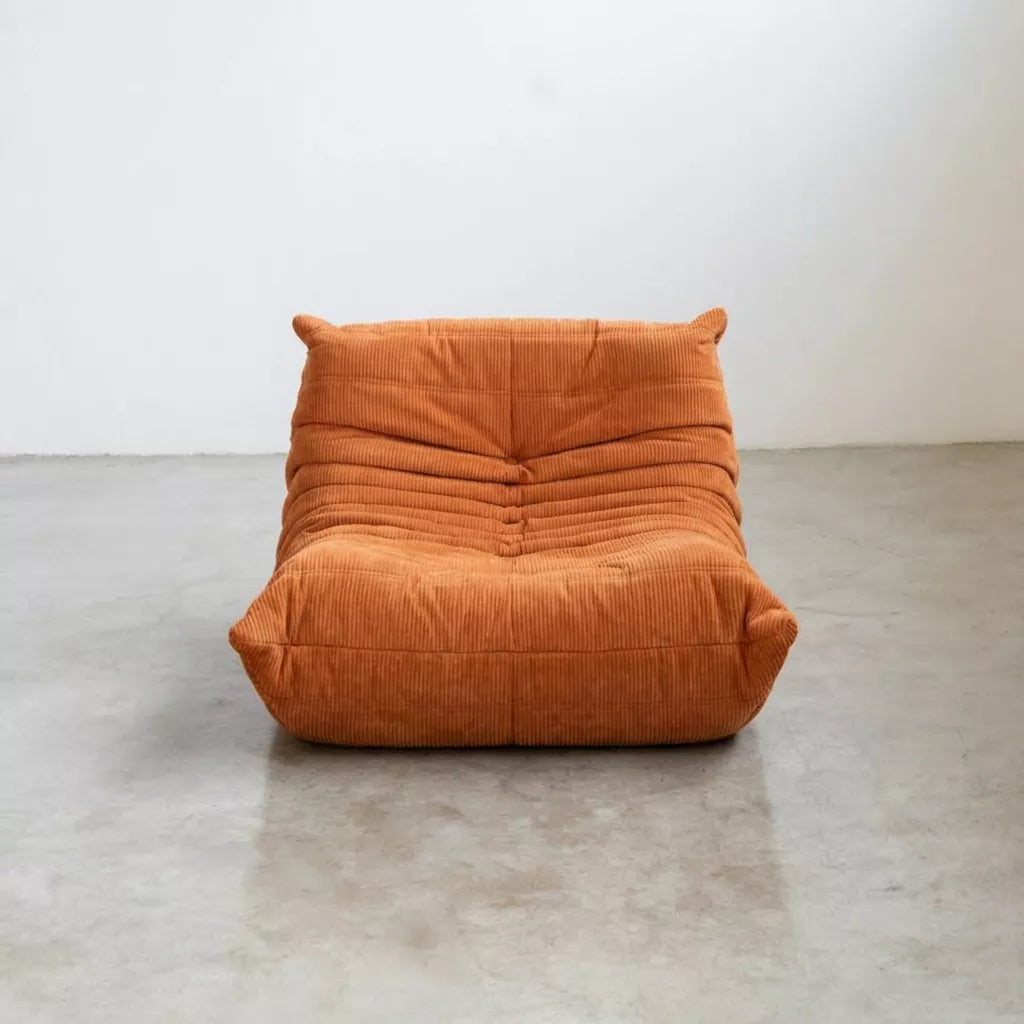 Replica of the orange corduroy Togo-chair by michael ducaroy– low, frameless design with plush channel tufting